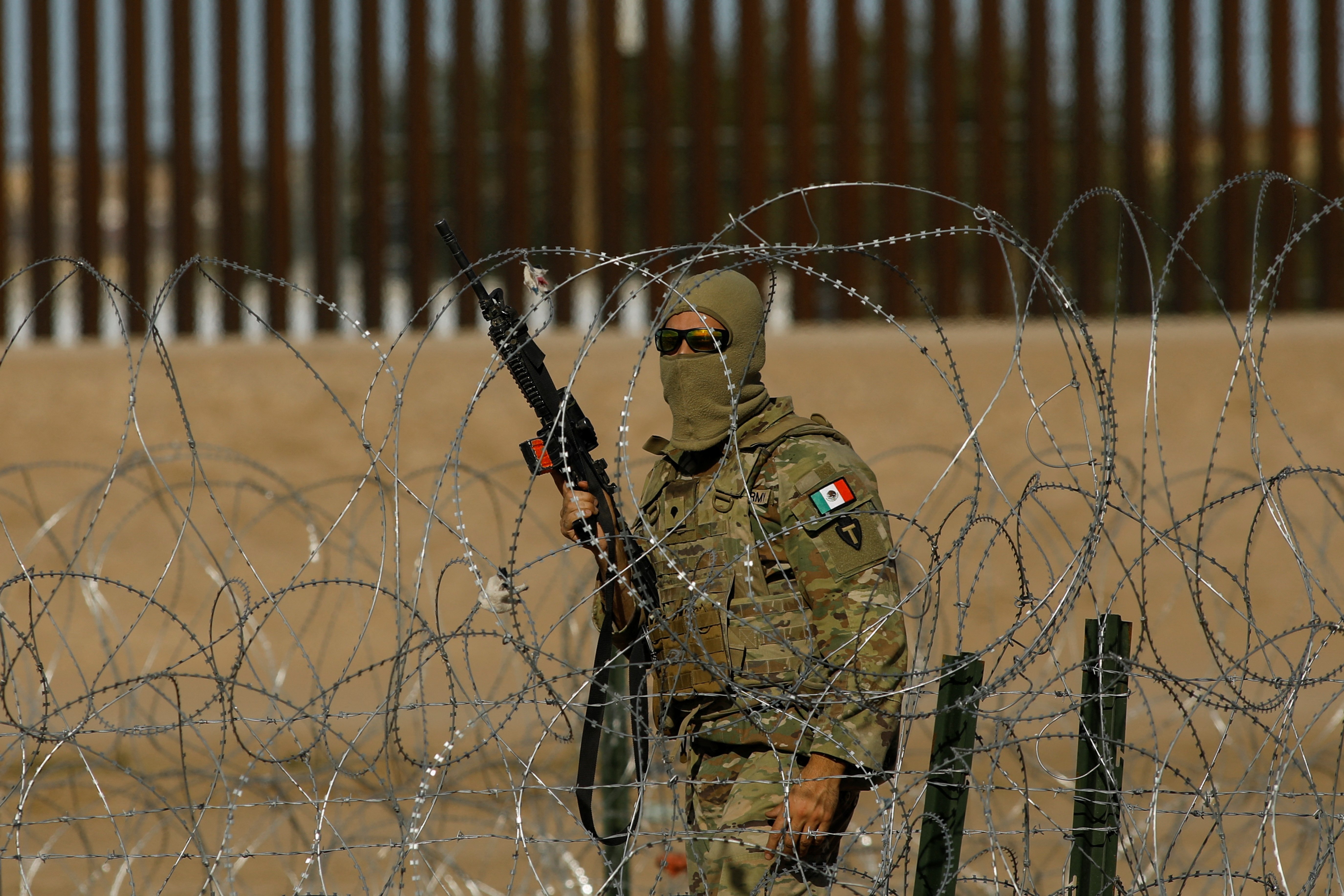 A member of the Texas National Guard stands guard on the banks of the Rio Bravo river, the border between the United States and Mexico, to prevent migrants from crossing into the United States, as seen from Ciudad Juarez, Mexico, December 5, 2023.