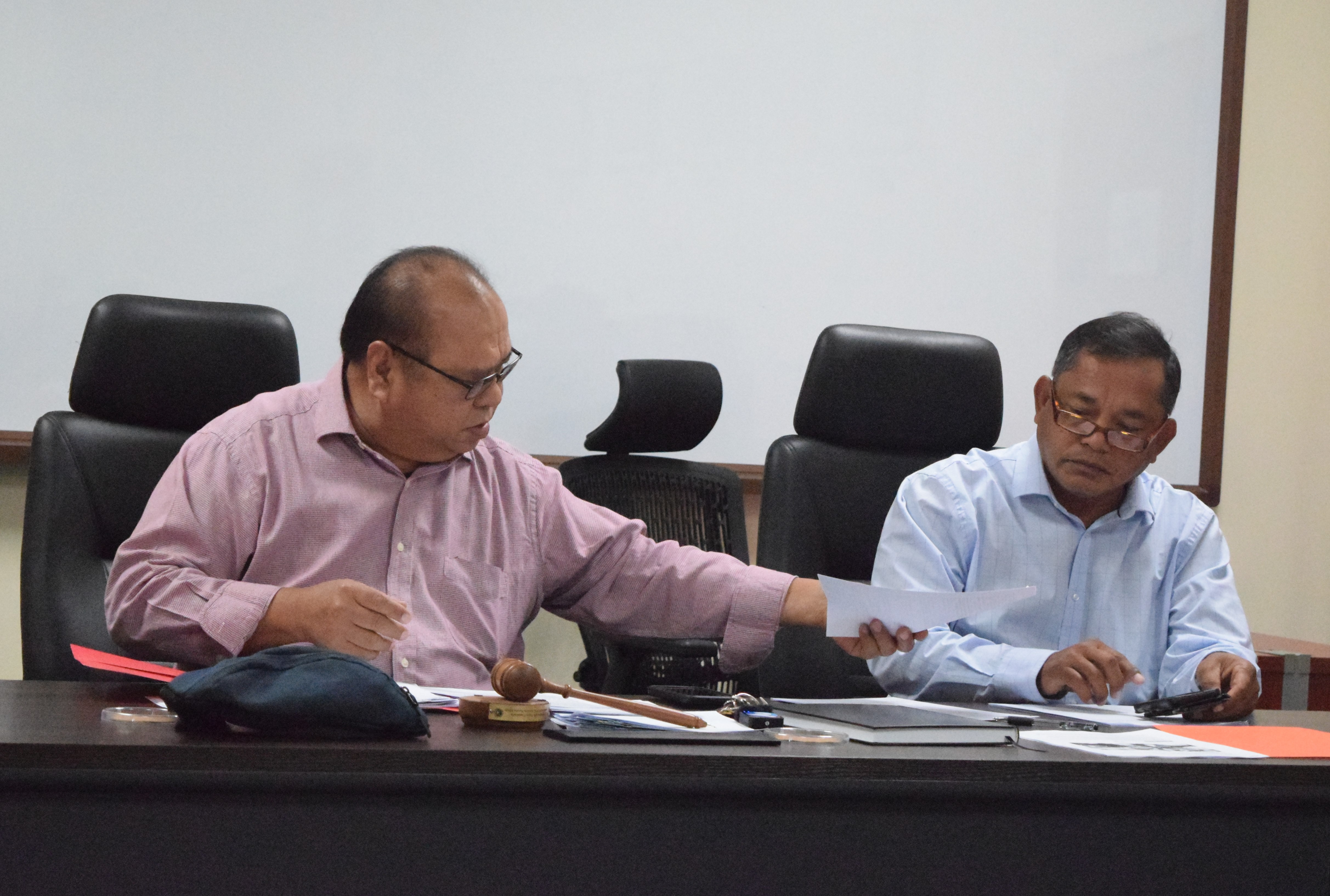 Commonwealth Casino Commission Chairman Edward C. Deleon Guerrero, left, hands a copy of a document to Vice Chairman Ralph S. Demapan during a meeting in Gualo Rai last week.