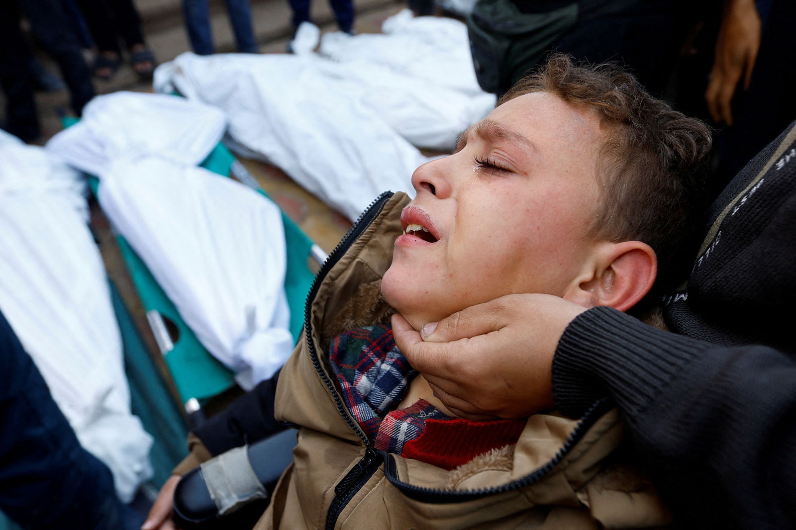 A Palestinian boy, who was injured in an Israeli raid reacts, as he attends the funeral of family members who were killed in the raid, amid the ongoing conflict between Israel and the Palestinian Islamist group Hamas, at Nasser hospital in Khan Younis, in the southern Gaza Strip, December 10, 2023. 