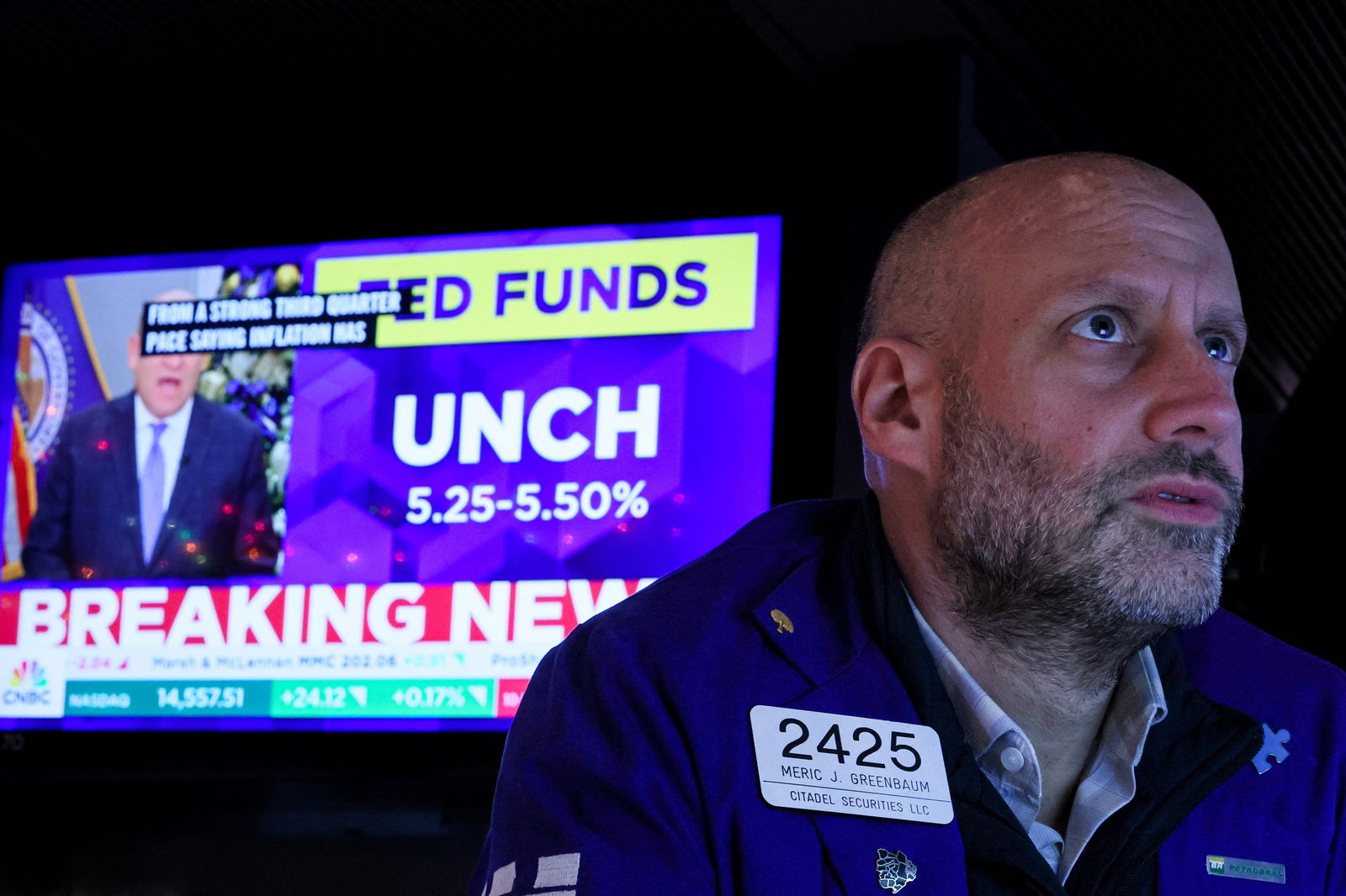 A trader reacts as a screen displays the Fed rate announcement on the floor of the New York Stock Exchange (NYSE) in New York City, U.S., December 13, 2023. 