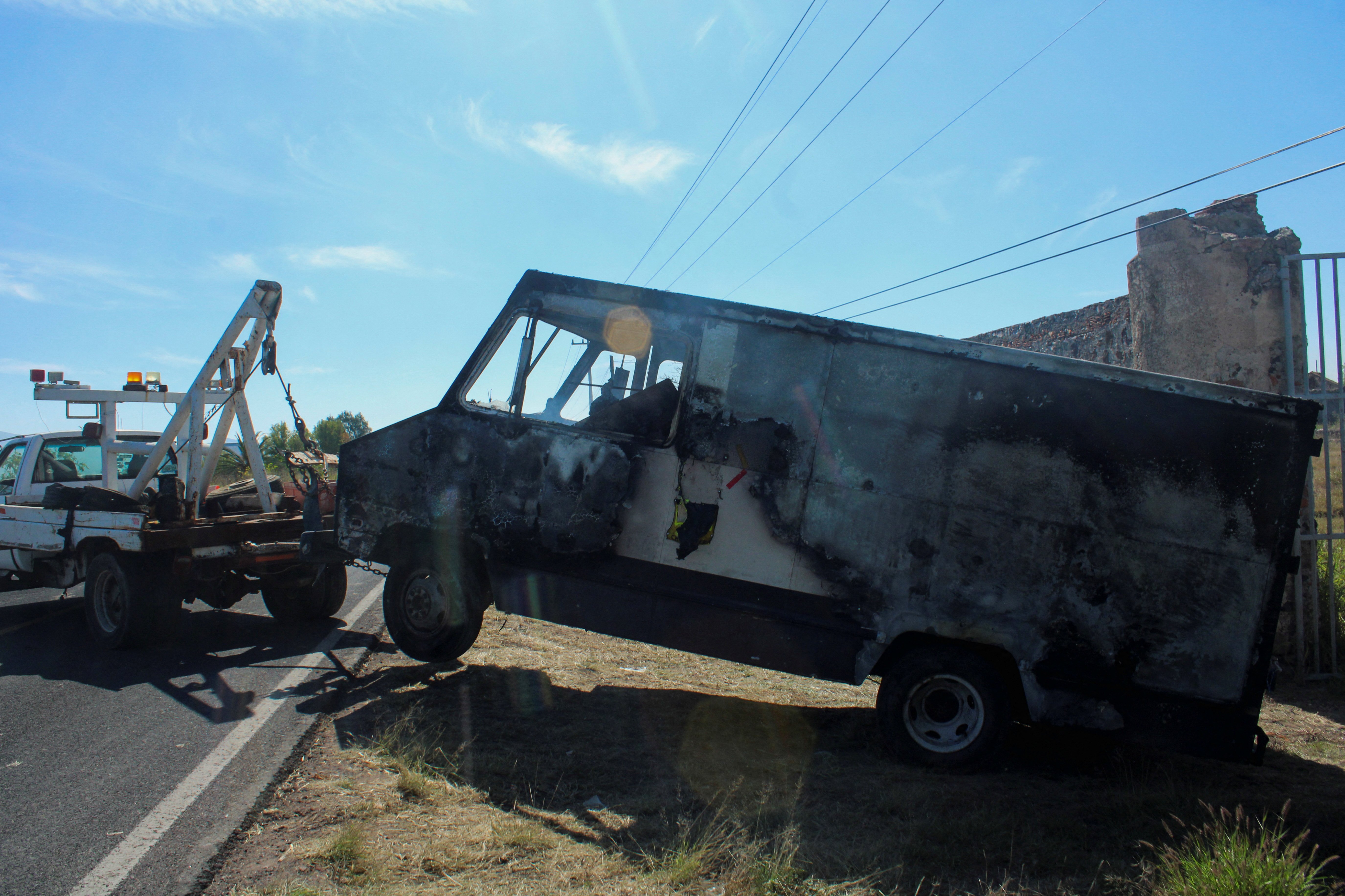 A tow truck moves the burnt wreckage of a truck off the scene where members of an armed group opened fire to partygoers attending a posada, in Salvatierra, in Guanajuato state, Mexico, December 17, 2023. 