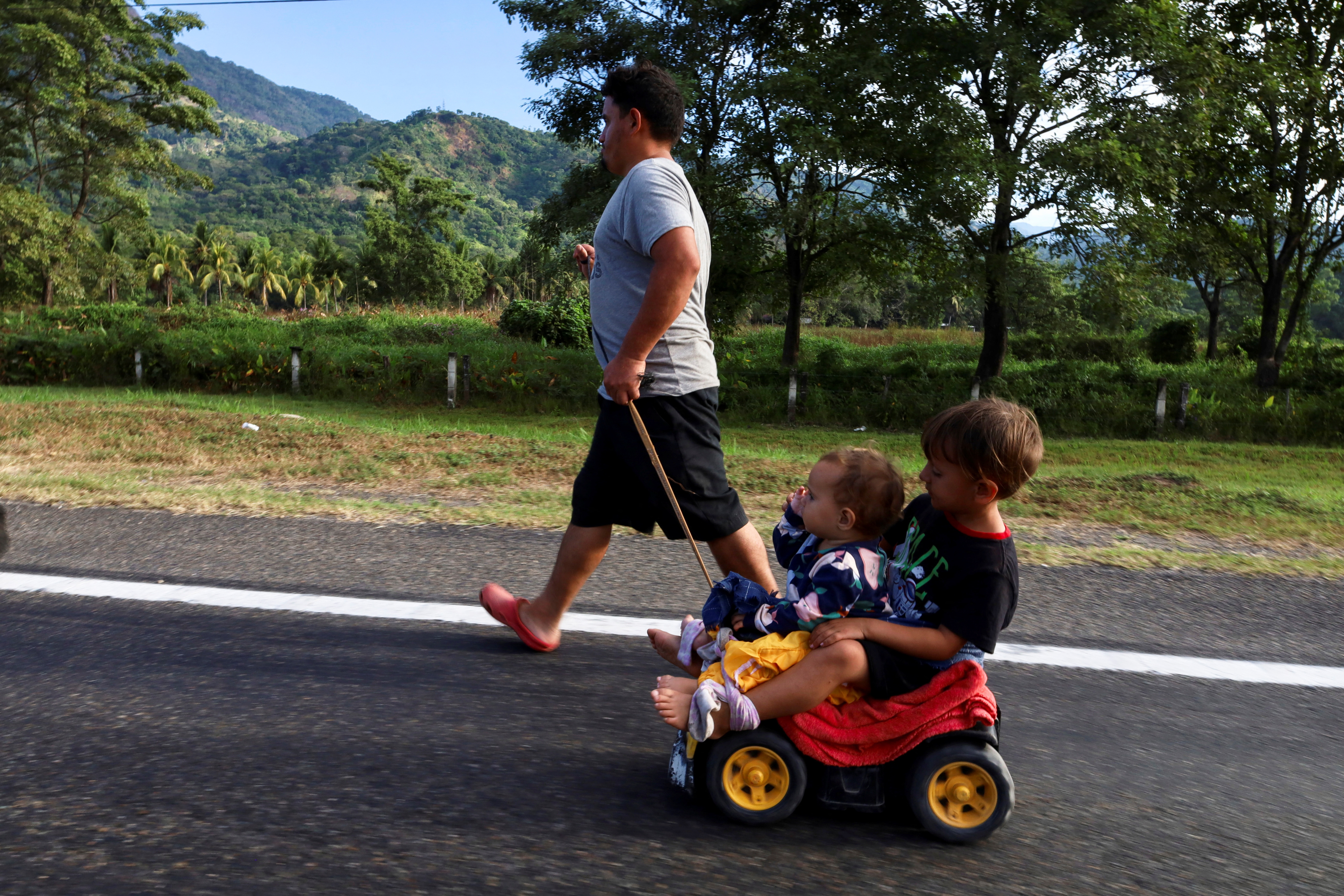 A migrant man pulls a toy car with his two children as he walks in a caravan in an attempt to reach the U.S. border, in Escuintla, Mexico, December 28, 2023.