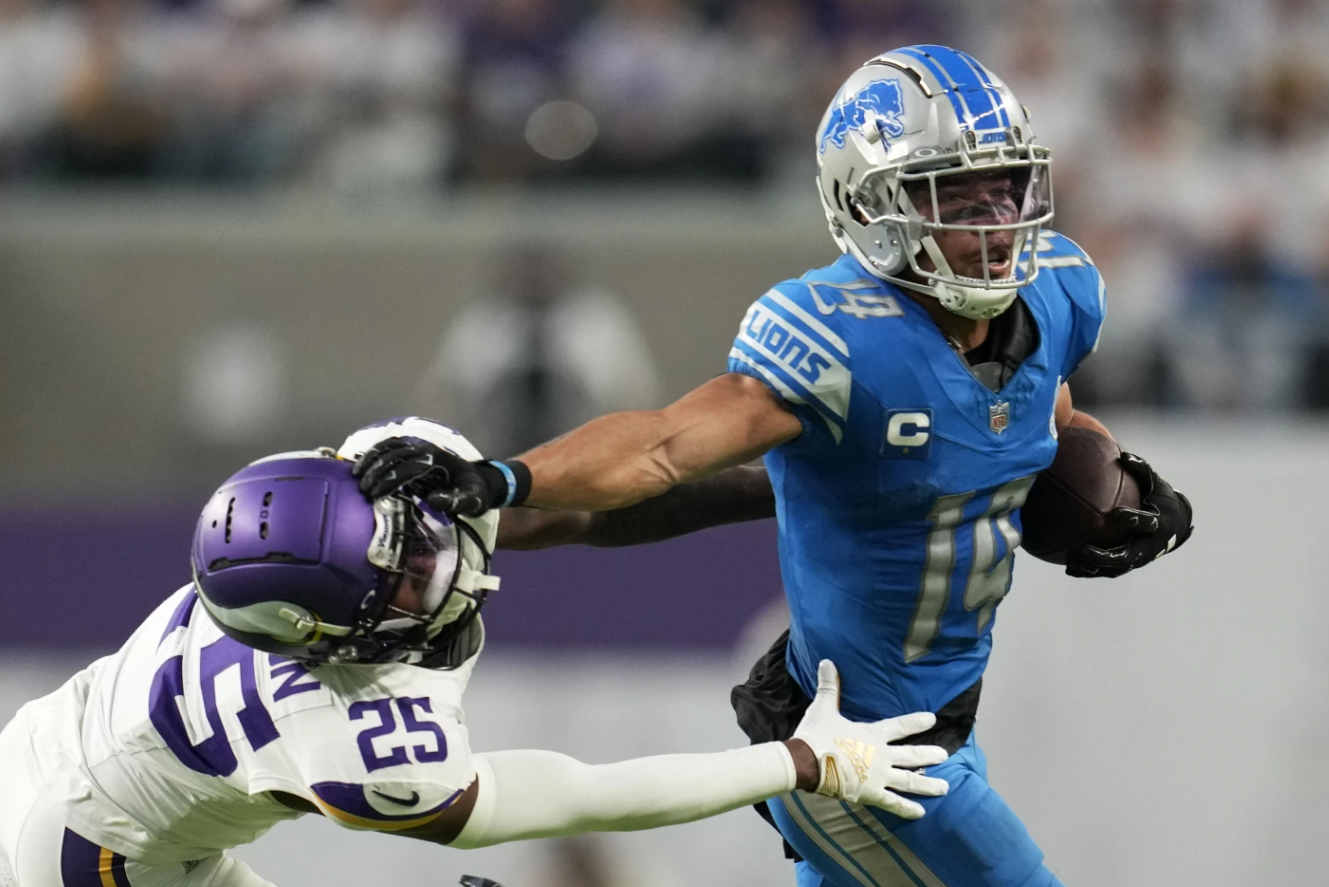 Detroit Lions wide receiver Amon-Ra St. Brown (14) breaks a tackle by Minnesota Vikings safety Theo Jackson (25) during the second half of an NFL game, Sunday, Dec. 24, 2023 in Minneapolis.