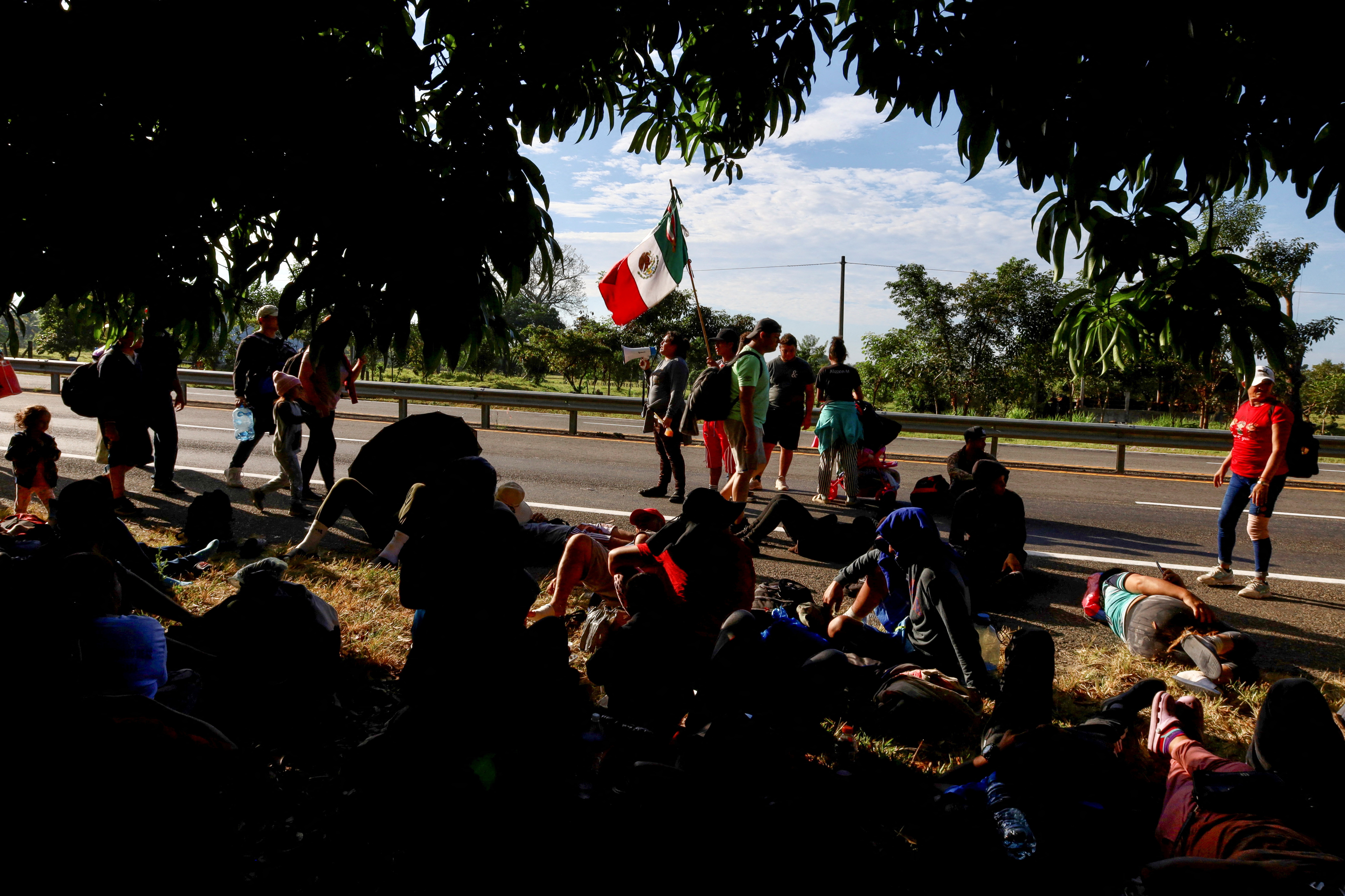 Migrants take a break on the side of the road before continuing walking in a caravan in an attempt to reach the U.S. border, in Escuintla, Mexico, December 28, 2023. 