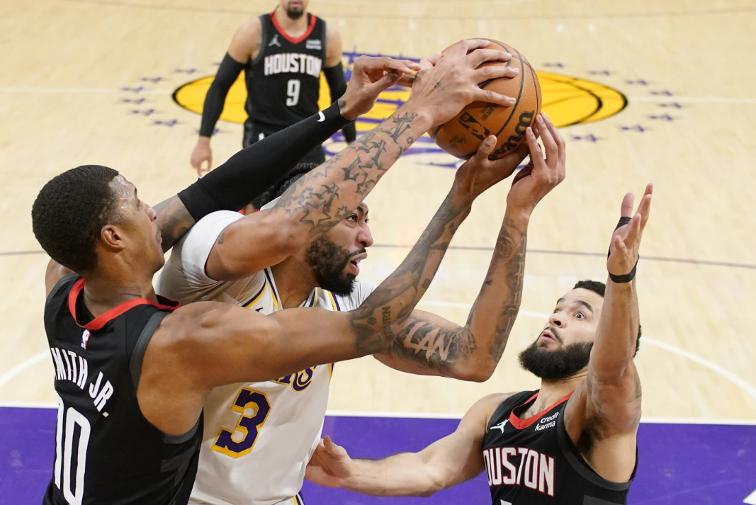 Los Angeles Lakers forward Anthony Davis, center, grabs rebound away from Houston Rockets forward Jabari Smith Jr., left, and guard Fred VanFleet during the first half of an NBA game Saturday, Dec. 2, 2023, in Los Angeles.
