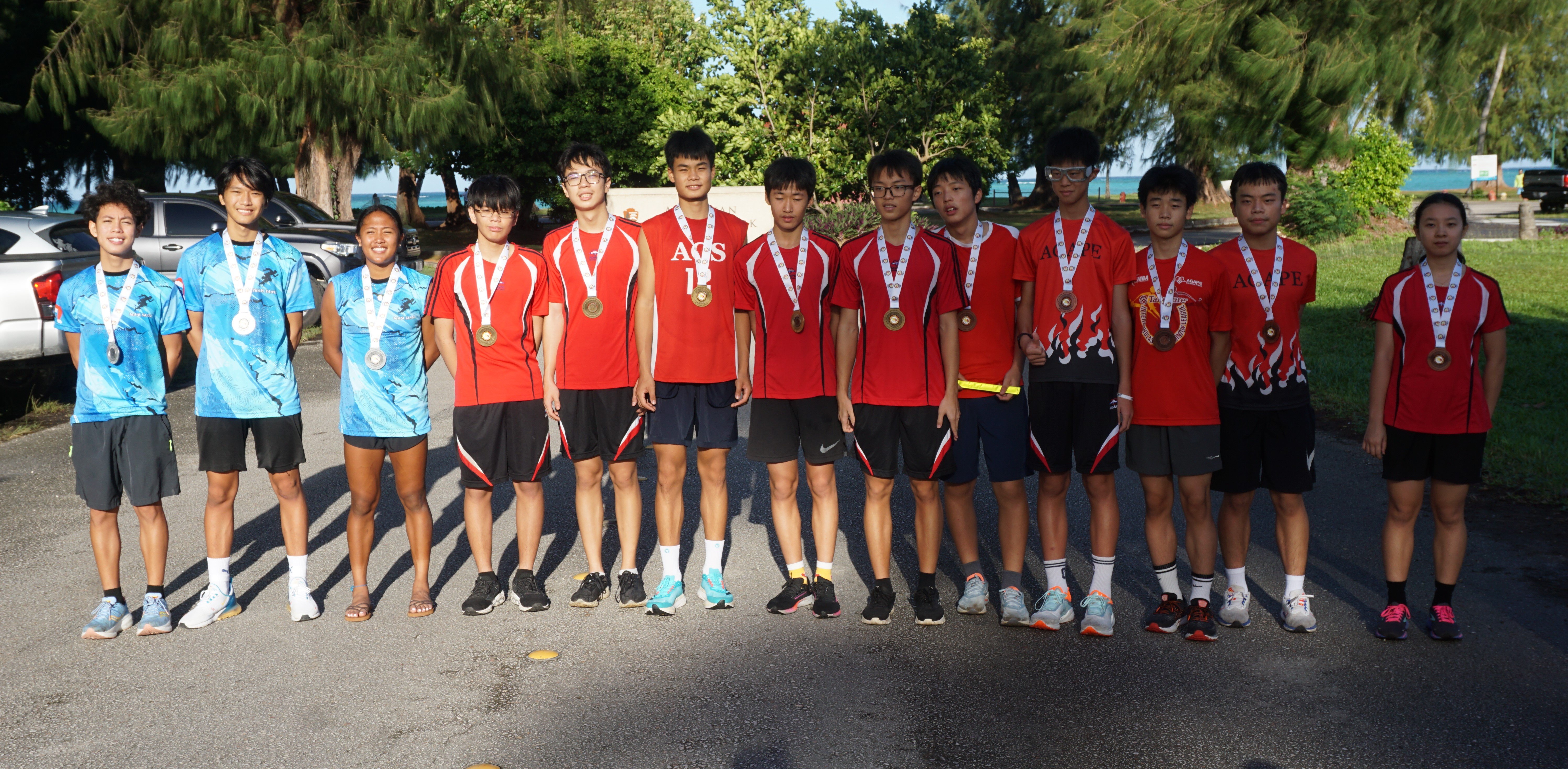 Agape Youth Team 1, center, Team Santa Youth 2023, left, and Agape Youth Team 2 pose for a photo with their finisher medals during the awards ceremony of the Annual Christmas Island Relay hosted by Northern Marianas Athletics at Micro Beach on Saturday.