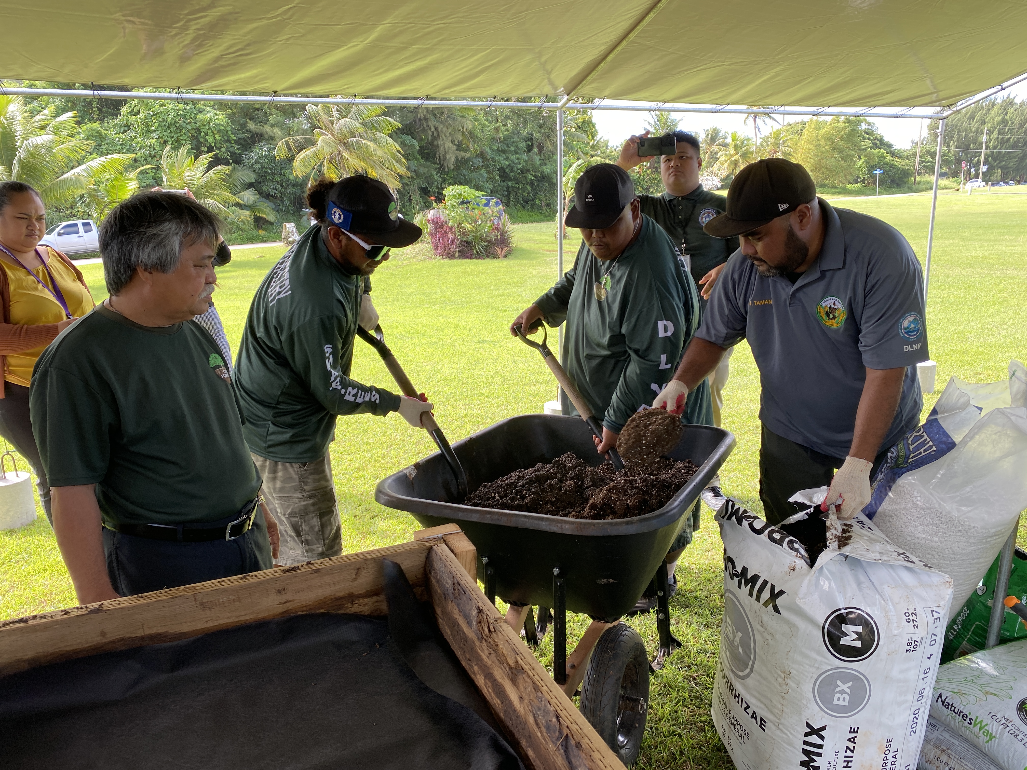 Division of Agriculture staff mix soil medium prior to placing them in raised garden beds at the Center for Living Independently