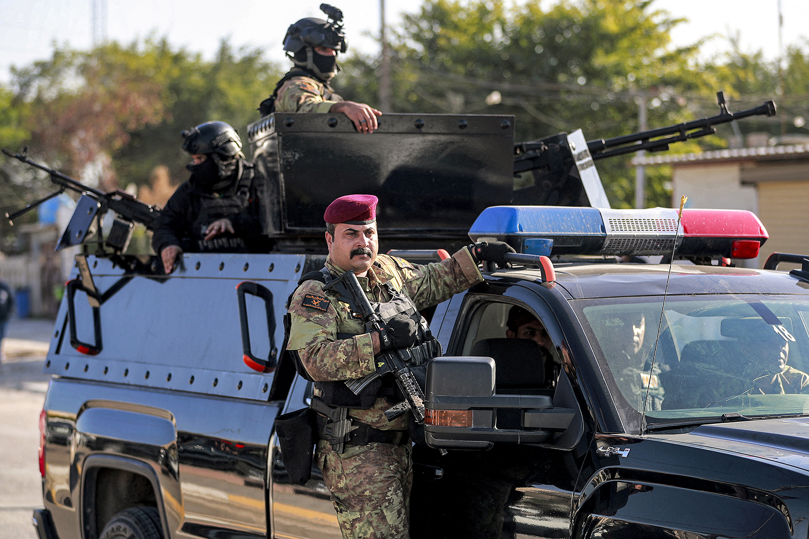Fighters of Iraq's Hashed al-Shaabi (Popular Mobilisation Forces - PMF) paramilitaries ride in vehicles moving in a convoy during the funeral of Hassan Hammadi al-Amiri, a fallen member of the group Kataeb Hezbollah, one of the factions of the PMF, in Baghdad on Dec. 26, 2023, after he was killed earlier in a US airstrike. US air strikes targeting a pro-Iranian group in Iraq on Dec. 26 claimed at least one life, drawing an angry response from Baghdad as regional tensions spike amid the Israel-Hamas war. (Ahmad Al-Rubaye/AFP via Getty Images/TNS)