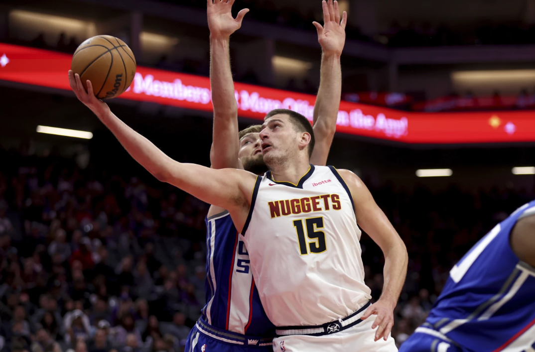 Denver Nuggets center Nikola Jokic (15) shoots against Sacramento Kings forward Domantas Sabonis, back, during the first half of an NBA game in Sacramento, Calif., Saturday, Dec. 2, 2023.