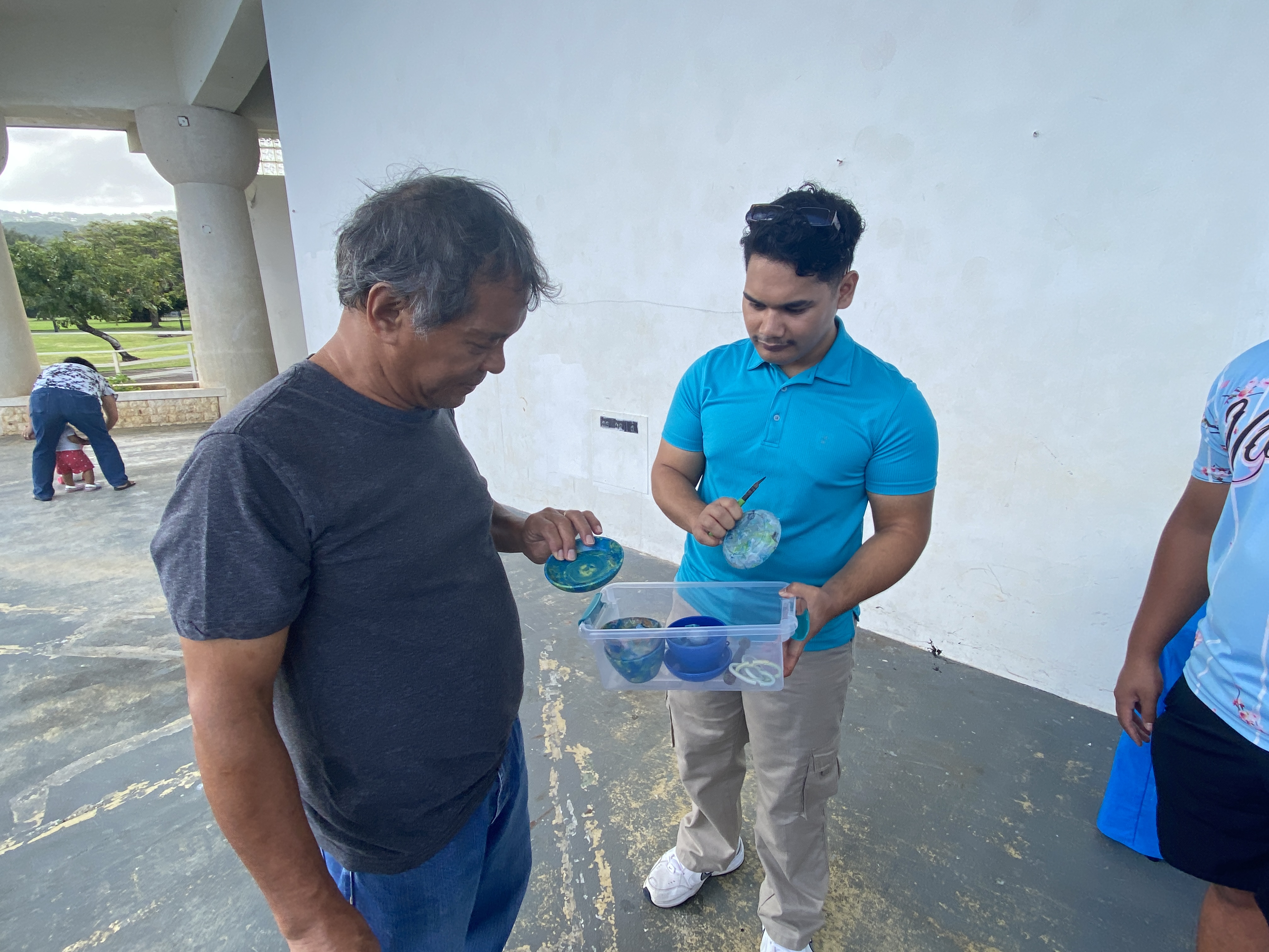 Joseph Nekaifes, right, shows a workshop participant the kind of plastic products that can be made with a 3-in-1 Upcycling Machine.