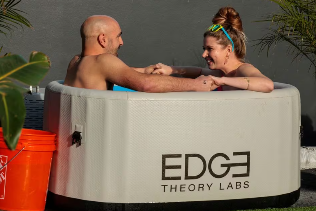Michael Brougham and Sarah Mitchell, both from Los Angeles, hold hands after entering an ice bath for three minutes of speed dating, as people plunge into baths of freezing cold water to help break the ice, in Santa Monica, California, Dec. 16, 2023.
