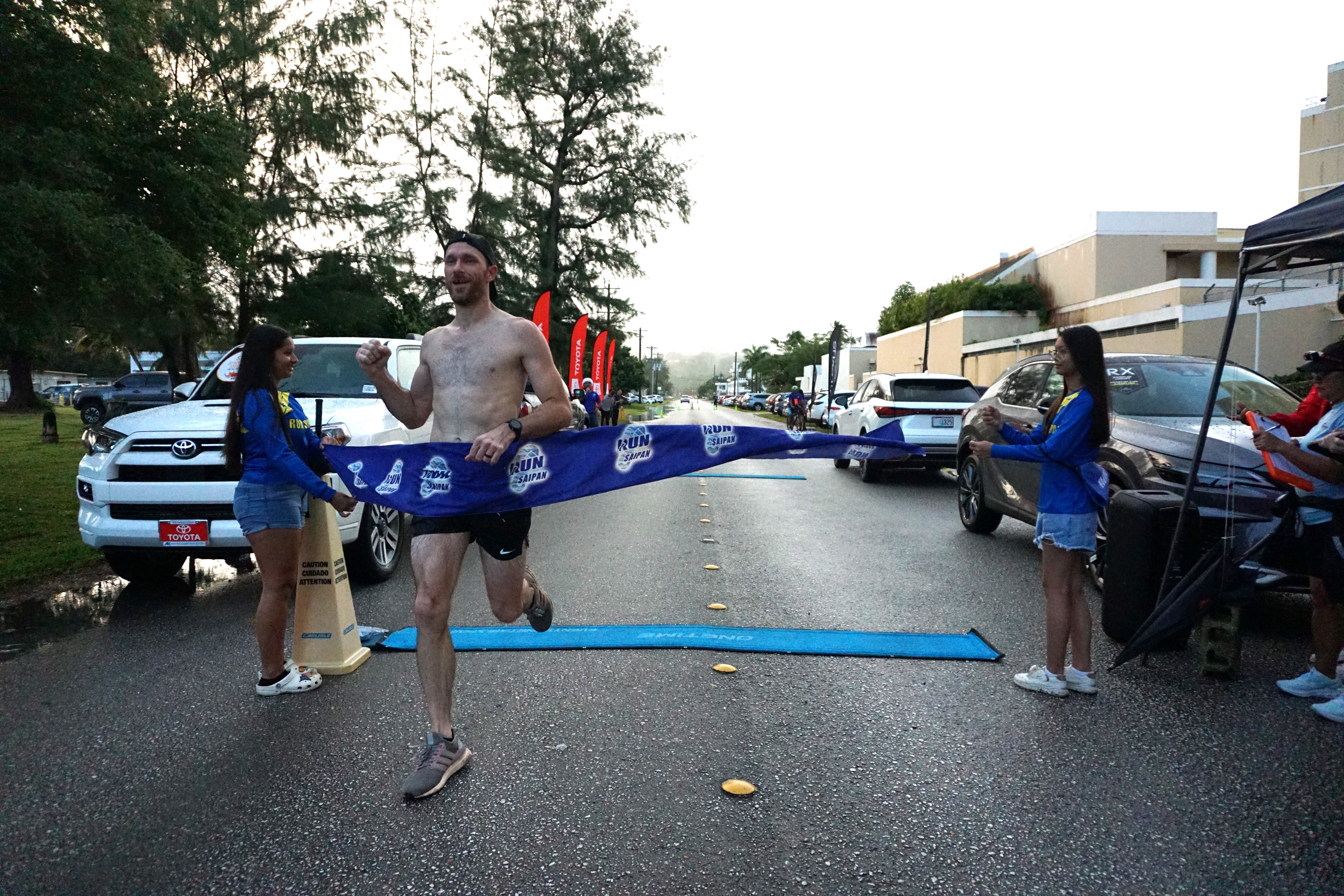 Joel Phair is the first to cross the finish line of the 2023 Run Saipan Holiday Half Marathon & AK 5K Fun Run at Micro Beach on Saturday.