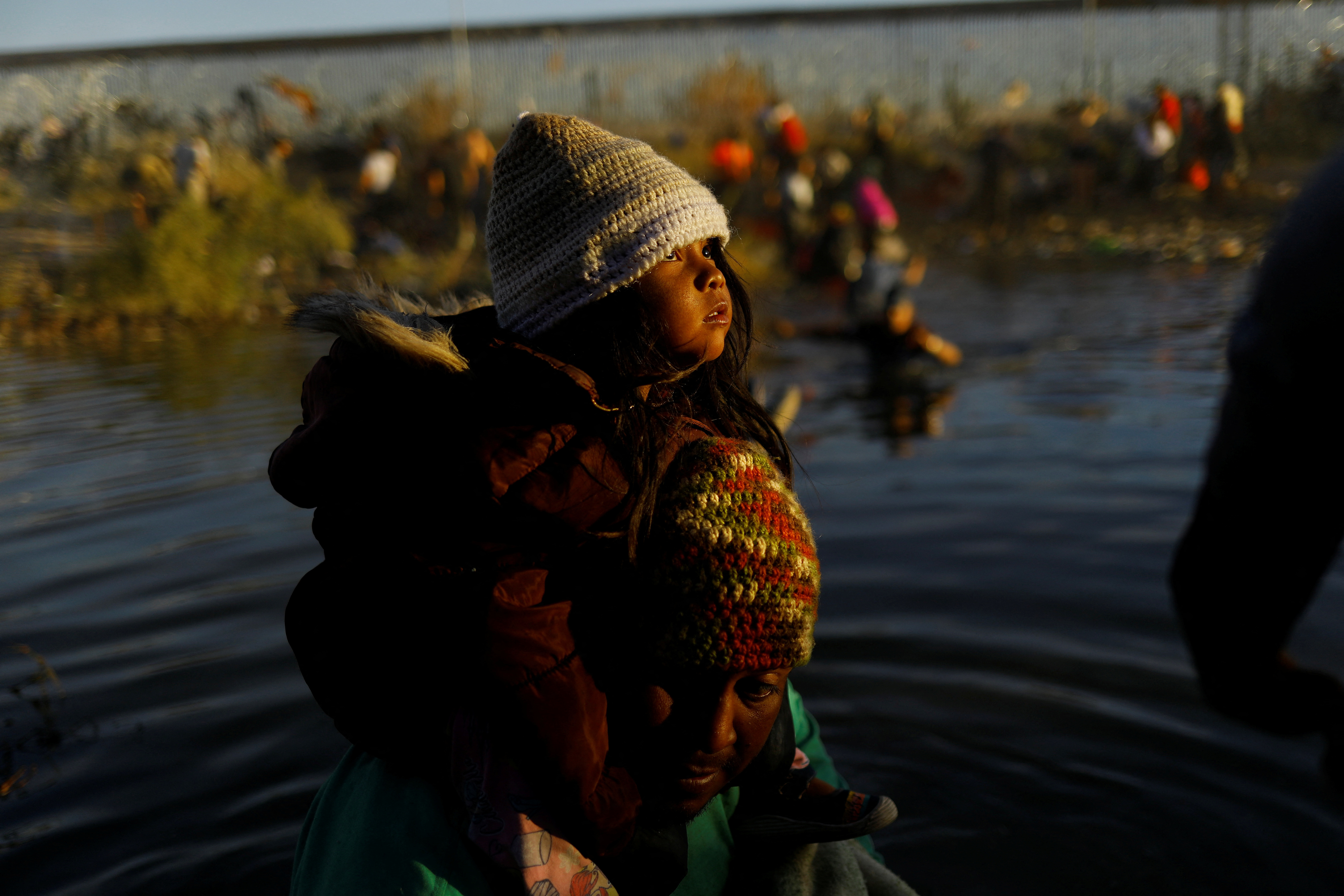Teo, a Venezuelan migrant, carries his daughter Sharill as they cross the Rio Bravo river, the border between the United States and Mexico, with the intention of turning themselves in to the U.S. Border Patrol agents to request asylum, during a day of low temperatures, as seen from Ciudad Juarez, Mexico December 28, 2023. 