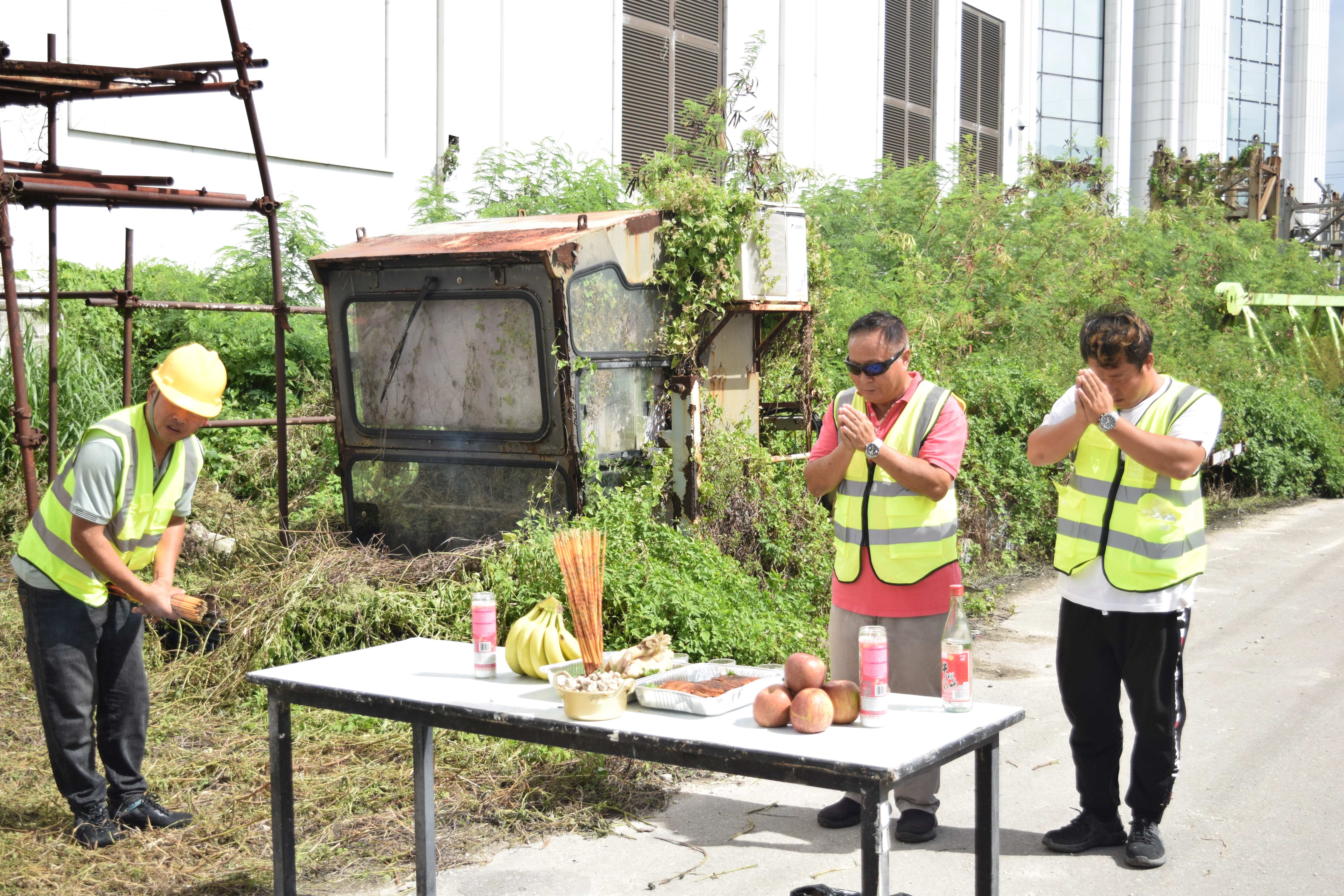 Ocean Bee LLC Manager He Guo Qiang and two of his staffers perform a Feng Shui ritual to mark the beginning of the Imperial Pacific International’s tower crane deconstruction project on Friday.