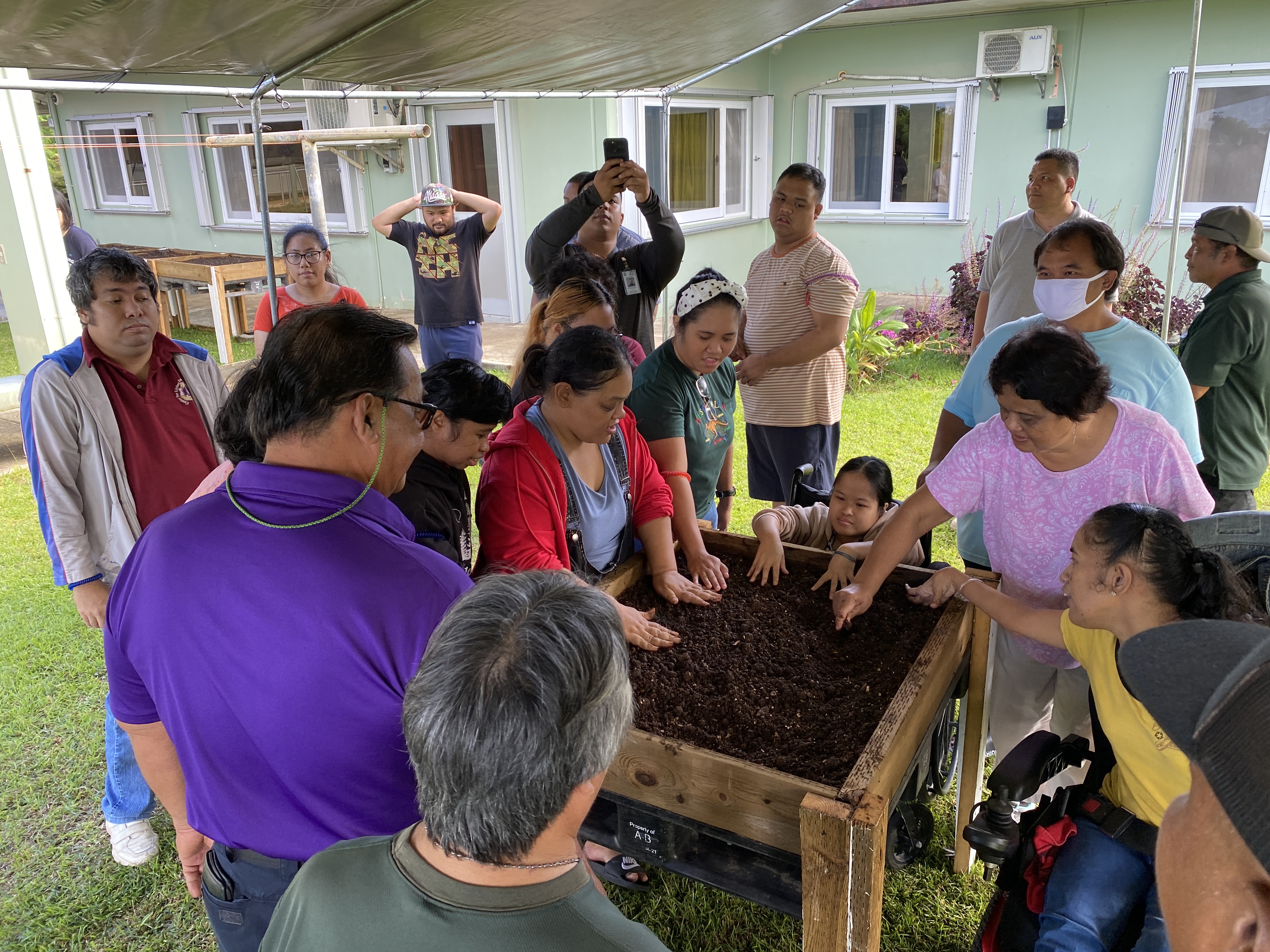 CLI consumers and the mayor inspect the raised garden bed after soil was placed in it.