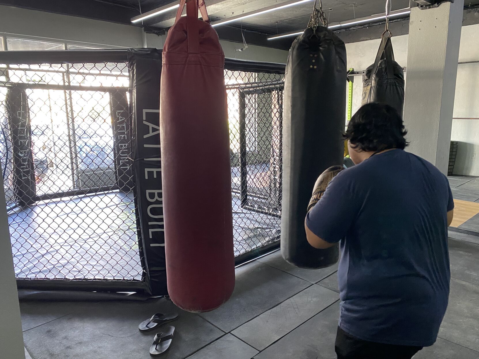 A Latte Built member uses the punching bags in the gym. Behind the punching bags is the gym's new mixed martial arts cage.