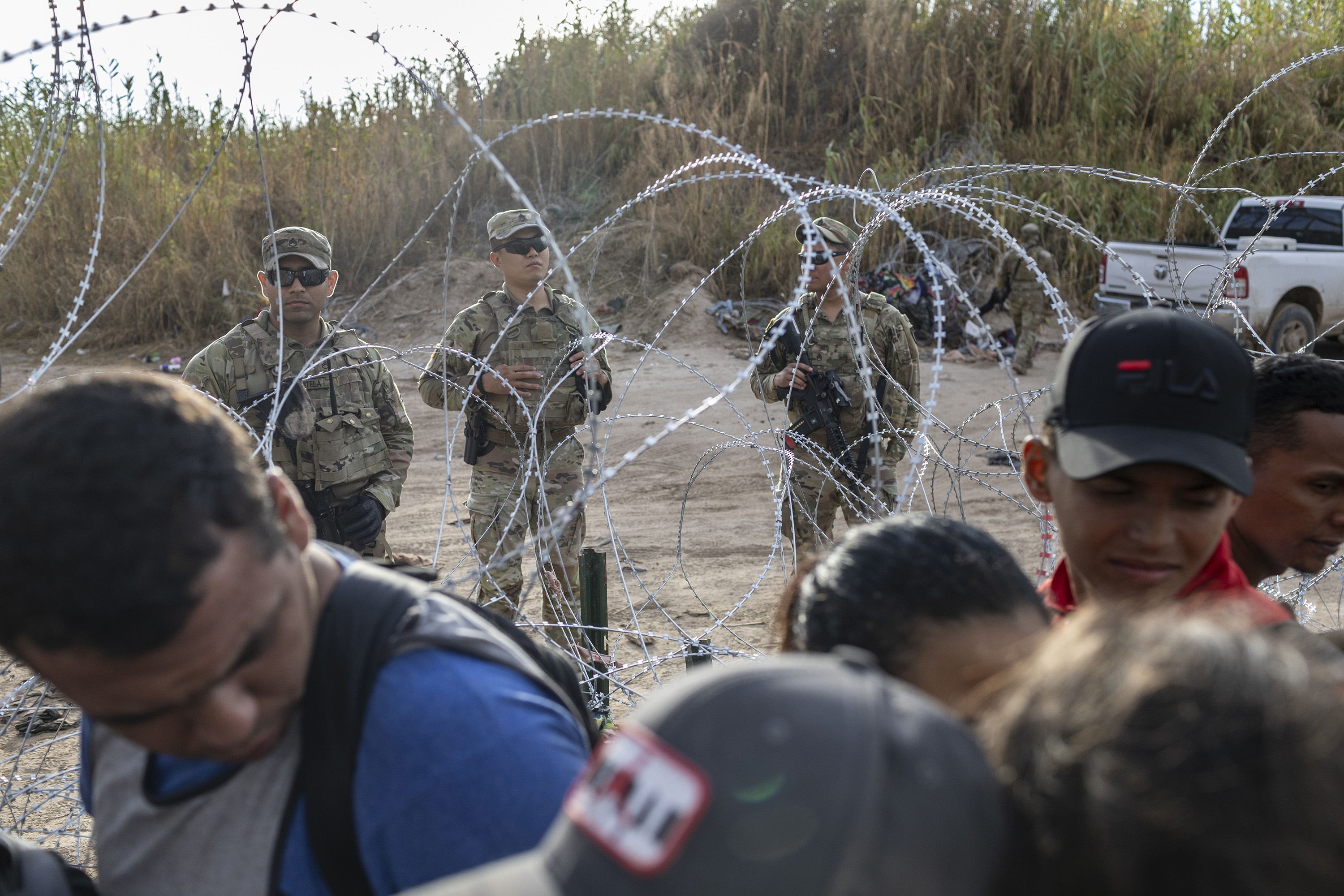 Texas National Guard soldiers stand vigil as asylum seekers wait to be processed by U.S. Border Patrol agents after crossing from Mexico into the United States on Sept. 30, 2023, in Eagle Pass, Texas. (John Moore/Getty Images/TNS)