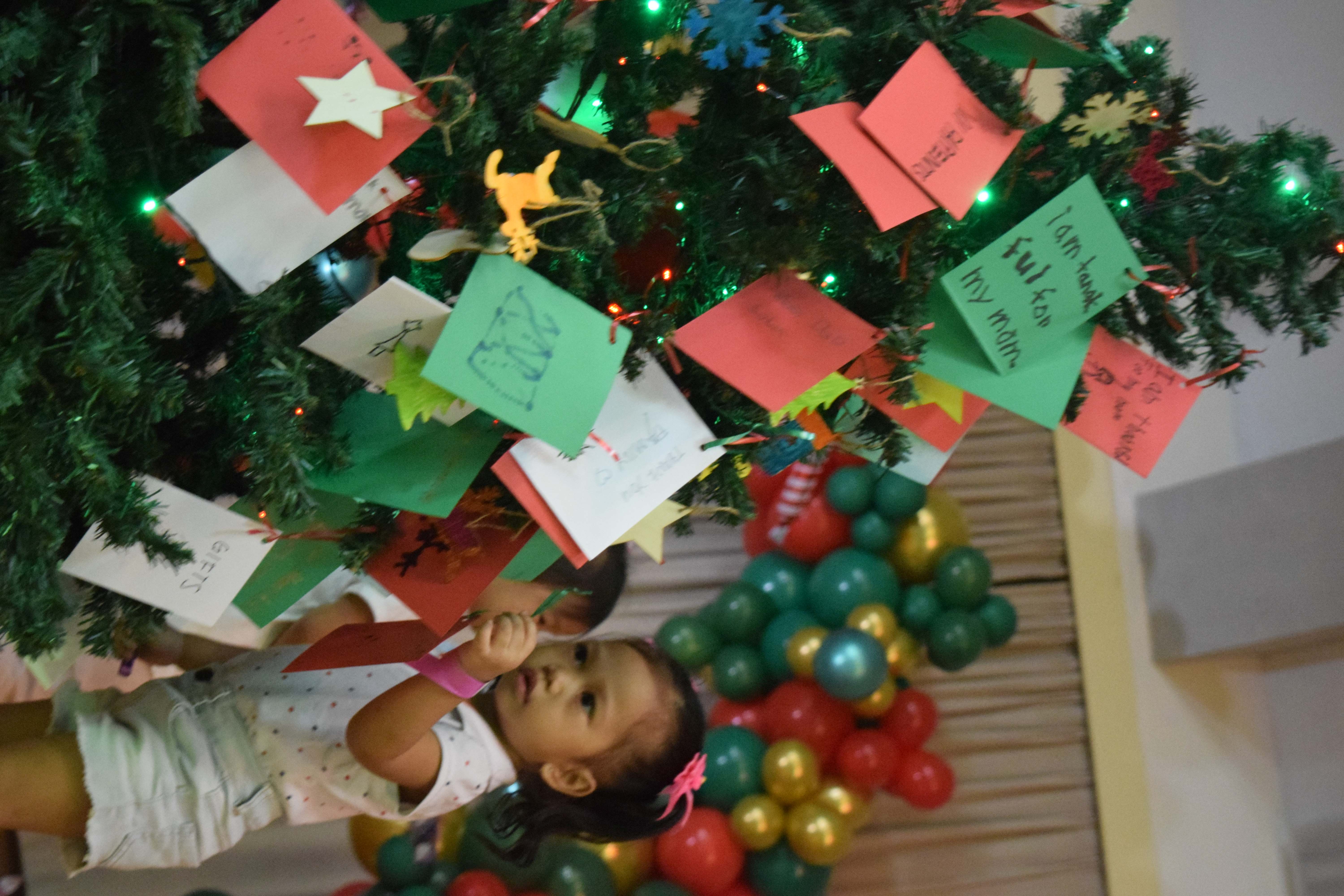  Iris Fernandez, 2, hangs her wish-card on a Christmas tree at the Gov. Pedro P. Tenorio Multi-Purpose Center on Saturday. 