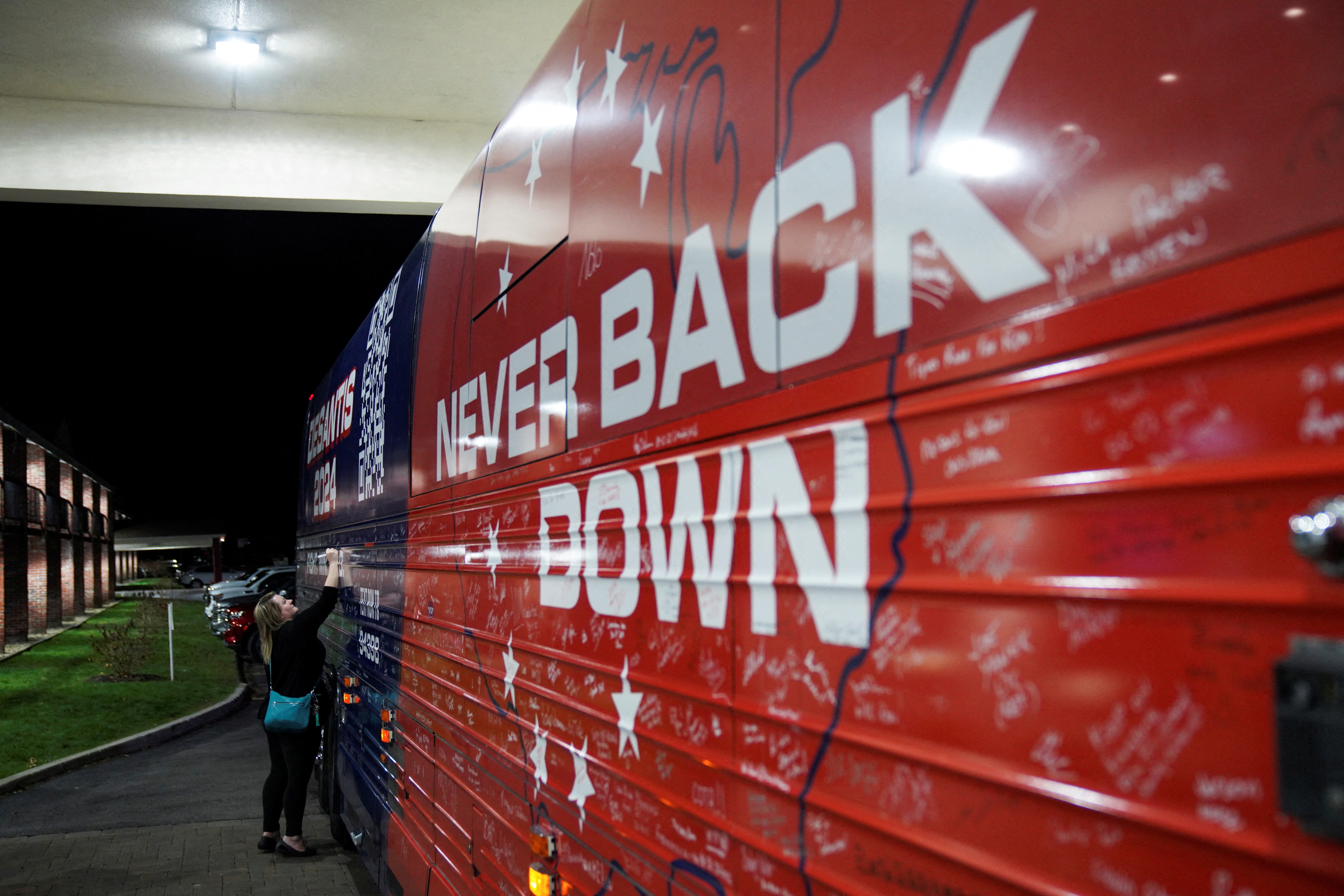New Hampshire resident Ellie Mooney, 44, signs the campaign bus of Republican presidential candidate Florida Governor Ron DeSantis after a Never Back Down campaign event in Keene, New Hampshire, U.S., on November 21, 2023. 