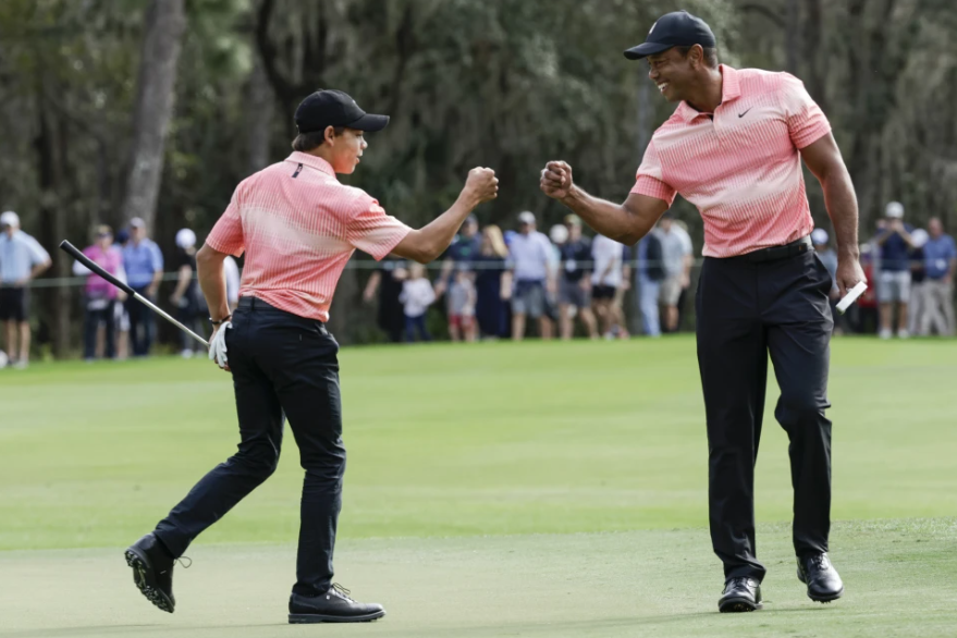 Tiger Woods, right, fist bumps his son Charlie Woods, left, after finishing the ninth hole during the first round of the PNC Championship golf tournament Saturday, Dec. 17, 2022, in Orlando, Fla.