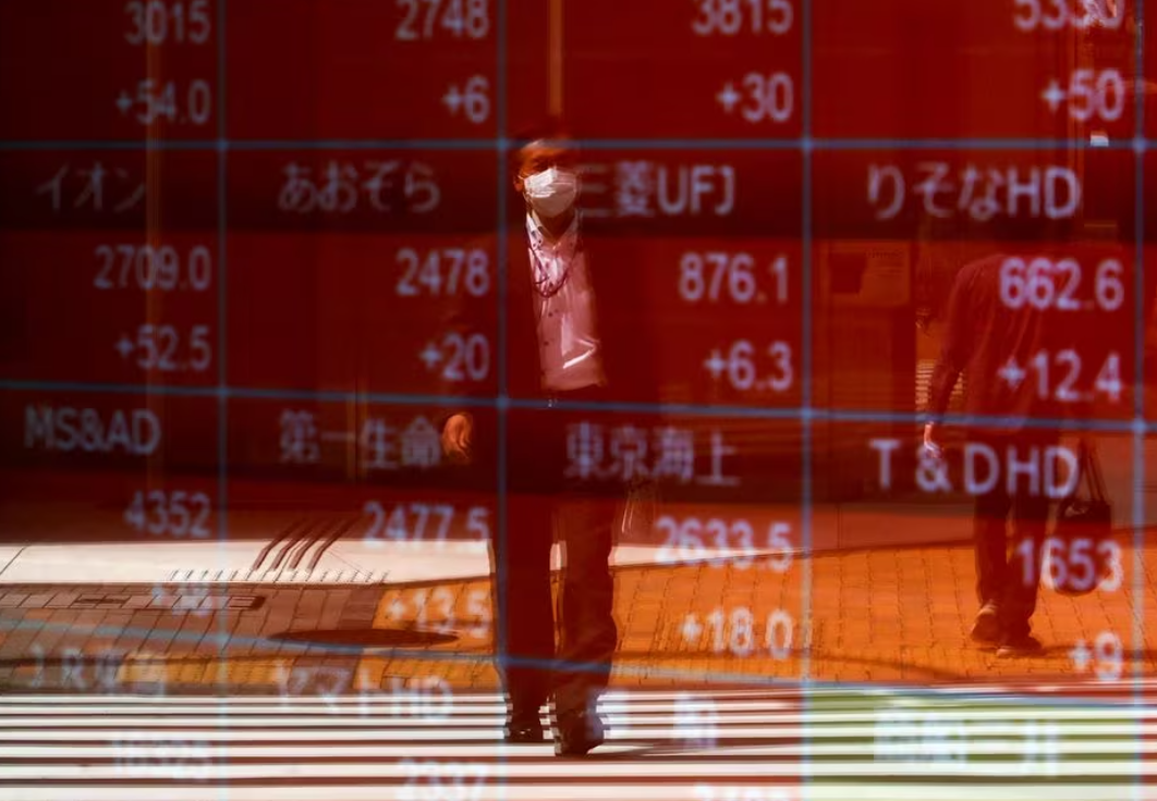 A man is reflected on an electric stock quotation board outside a brokerage in Tokyo, Japan, April 18, 2023.