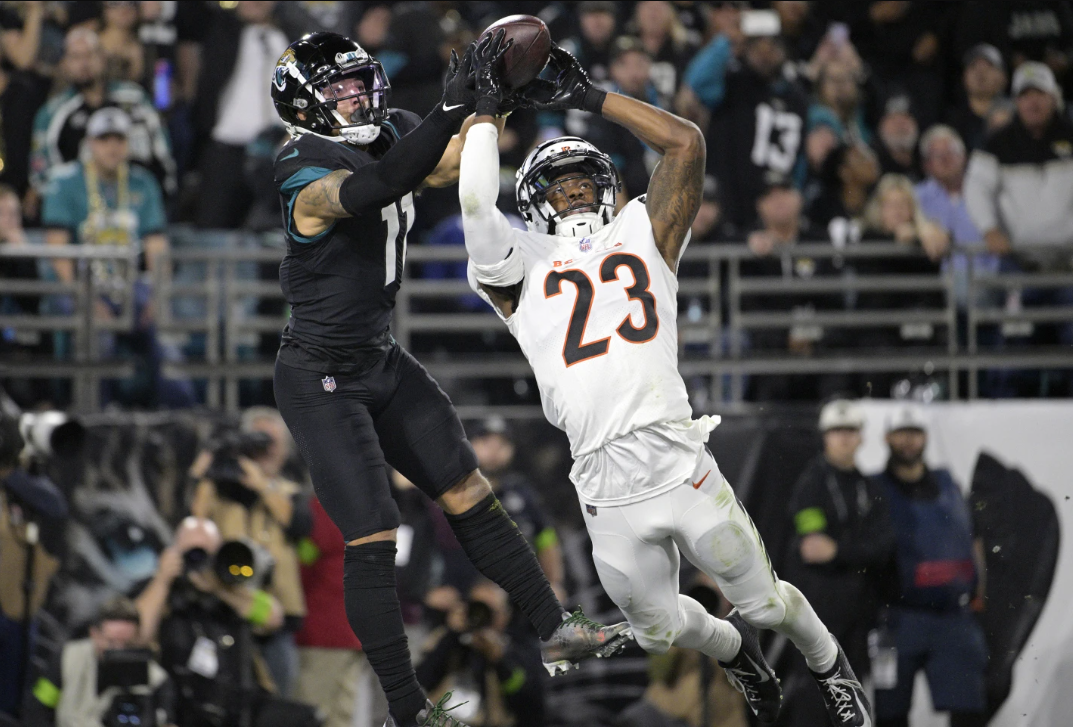 Jacksonville Jaguars wide receiver Parker Washington (11) grabs a pass in the end zone for a touchdown as Cincinnati Bengals safety Dax Hill (23) defends during the second half of an NFL game Monday, Dec. 4, 2023 in Jacksonville, Fla.