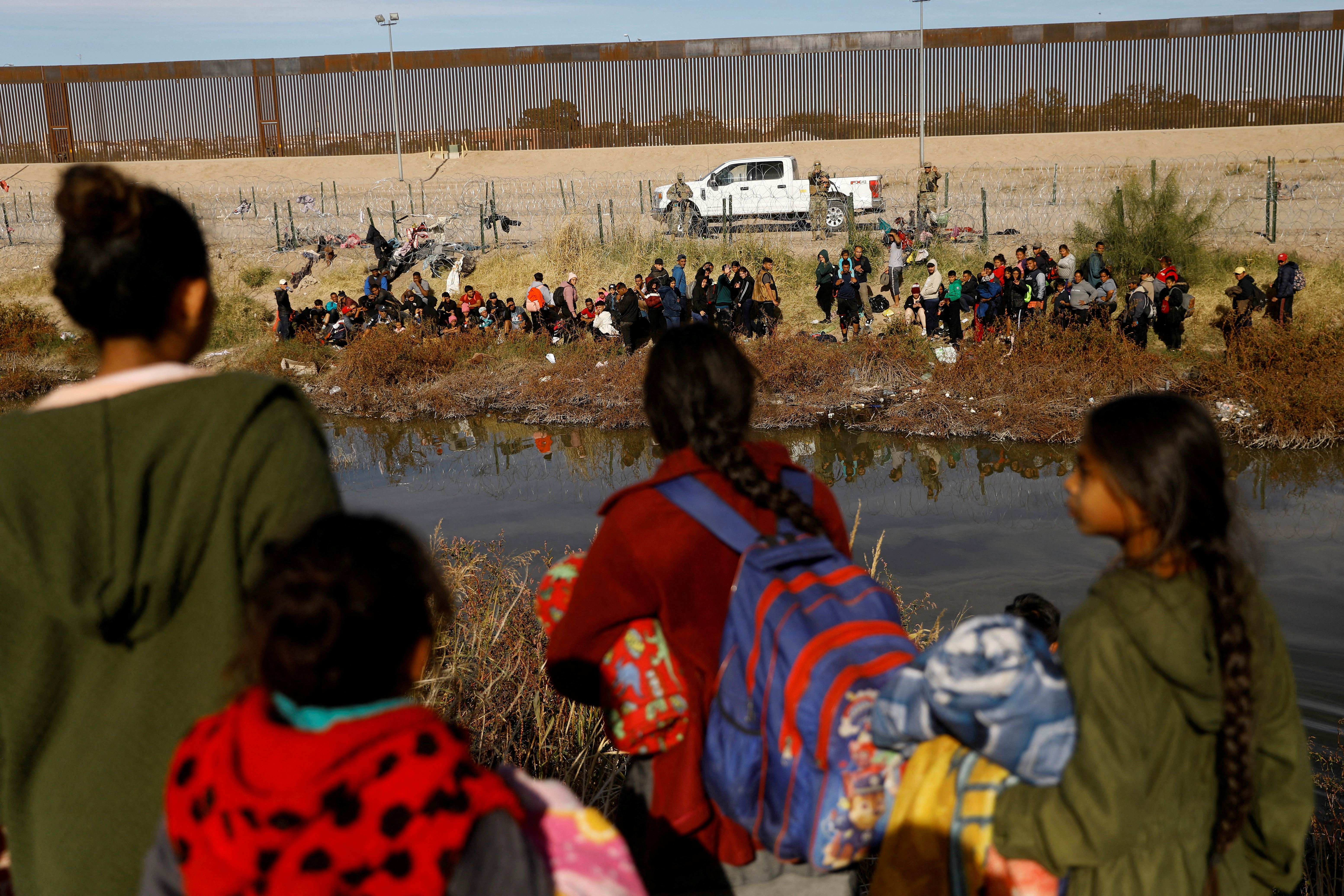 Migrants seeking asylum in the United States gather on the banks of the Rio Bravo river, as the Texas National Guard blocks the crossing at the border between the United States and Mexico, as seen from Ciudad Juarez, Mexico December 5, 2023. 