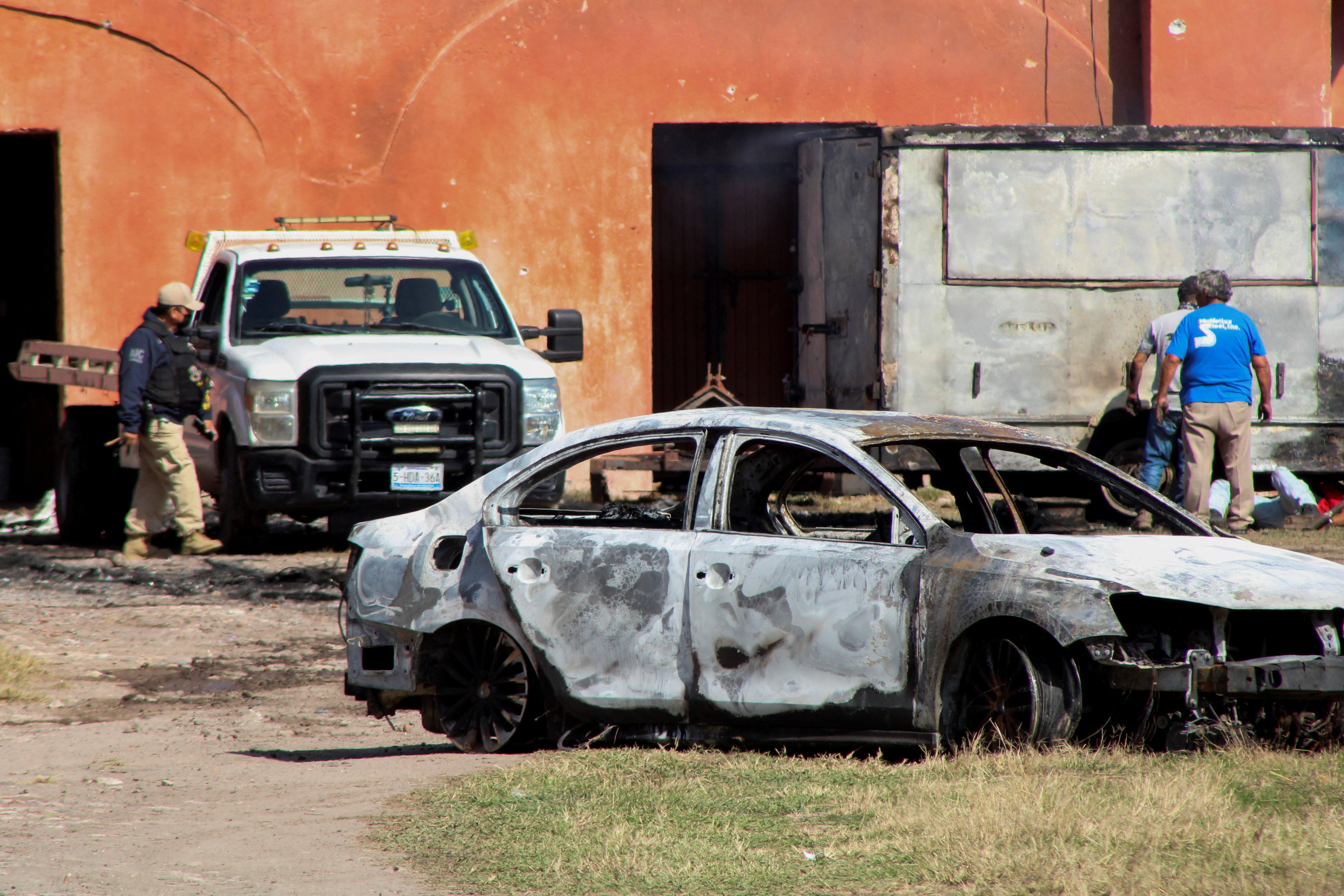 The burnt wreckage of a car stands at the scene where members of an armed group opened fire to partygoers attending a posada, in Salvatierra, in Guanajuato state, Mexico, December 17, 2023. 