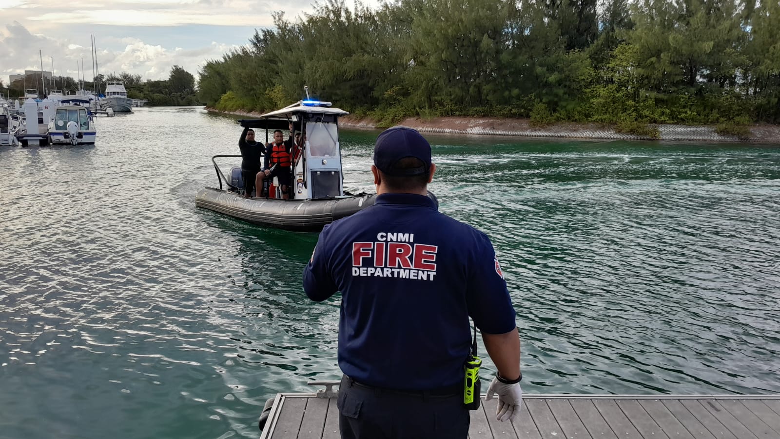 A fire department staffer, back to the camera, watches as a Department of Public Safety boat transporting three rescued fishermen arrives at Smiling Cove Marina on Wednesday afternoon.