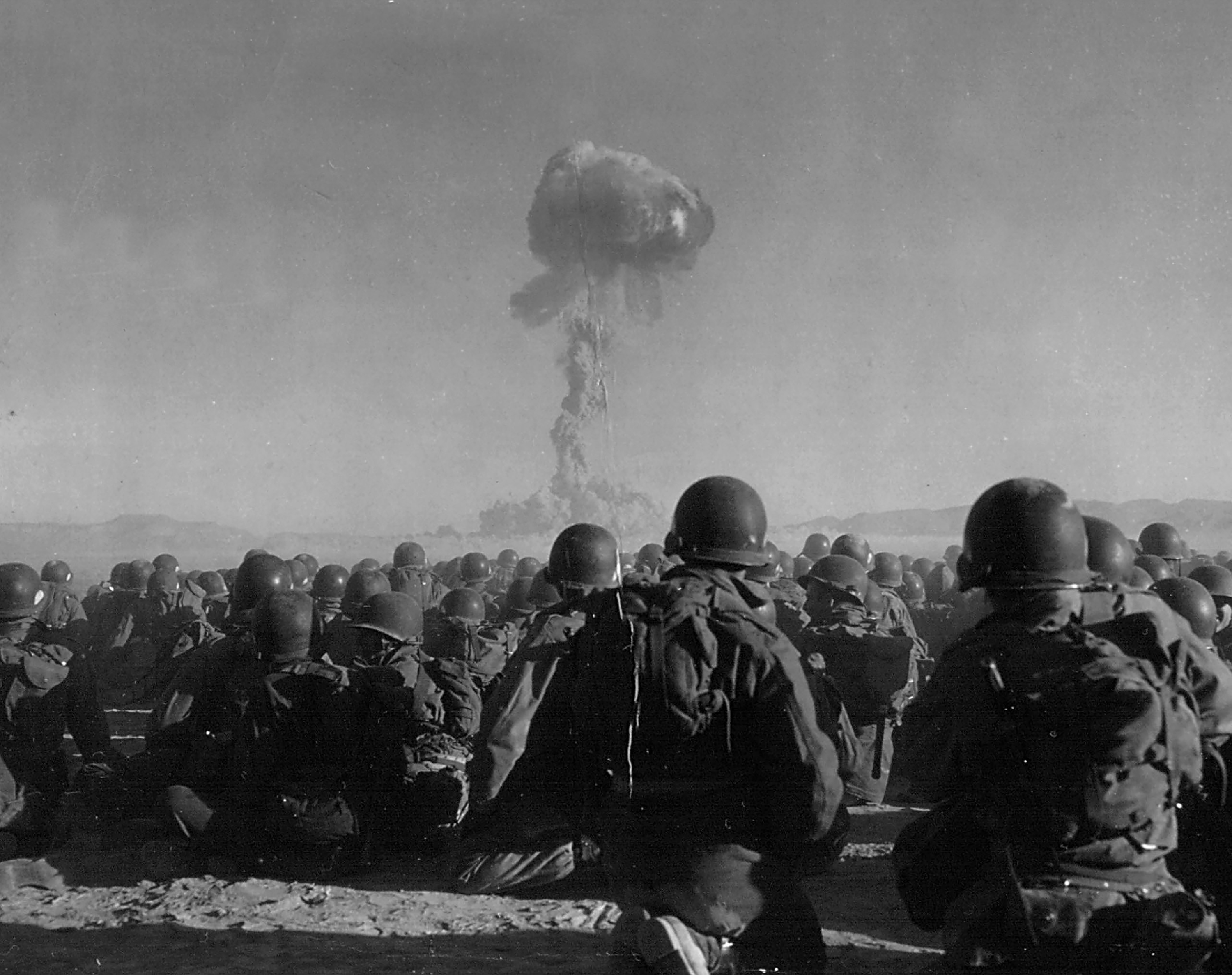 Troops of the U.S. Army 11th Airborne Division watch a plume of radioactive smoke rise on Nov. 1, 1951, after a blast at Yucca Flats, Nevada. 