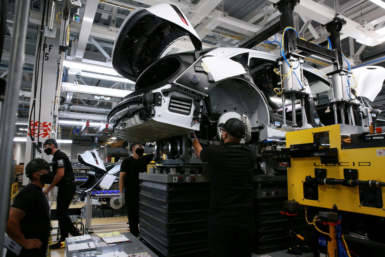 Workers marry the body structure with the battery pack and the front and rear sub frames as they assemble electric vehicles at the Lucid Motors plant in Casa Grande, Arizona,  Sept. 28, 2021.