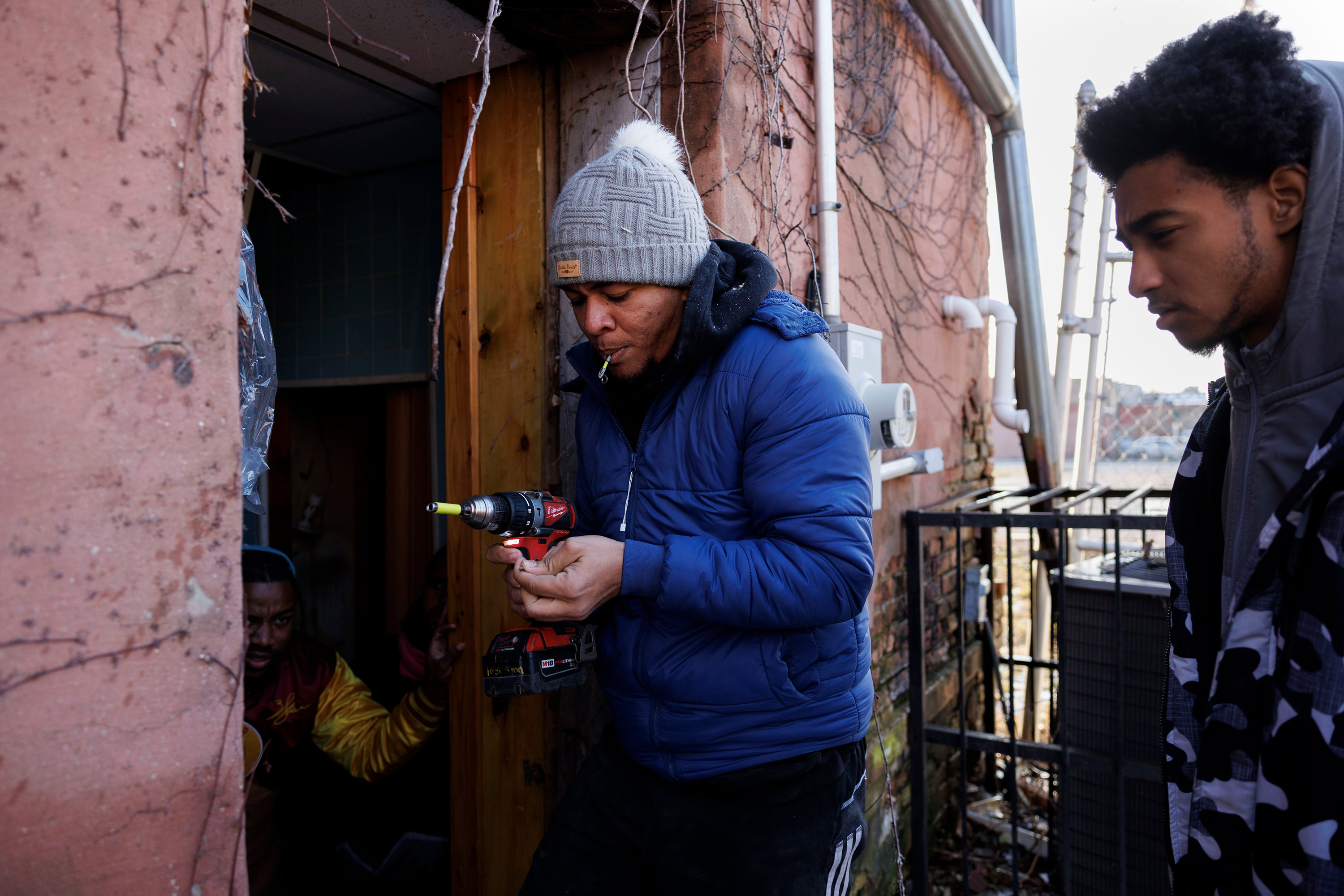 Matthew Anderson, 19, right, watches Rayni Cuadrado, 29, of Venezuela, change a drill bit on Jan. 11, 2024, while clearing debris from a broken doorway at New Promise Land Missionary Baptist Church in Chicago's North Lawndale neighborhood after it was broken into. Cuadrado, who had been going to Home Depot every day for a month, said it was his first substantial job after arriving in the U.S in November. (Armando L. Sanchez/Chicago Tribune/TNS)