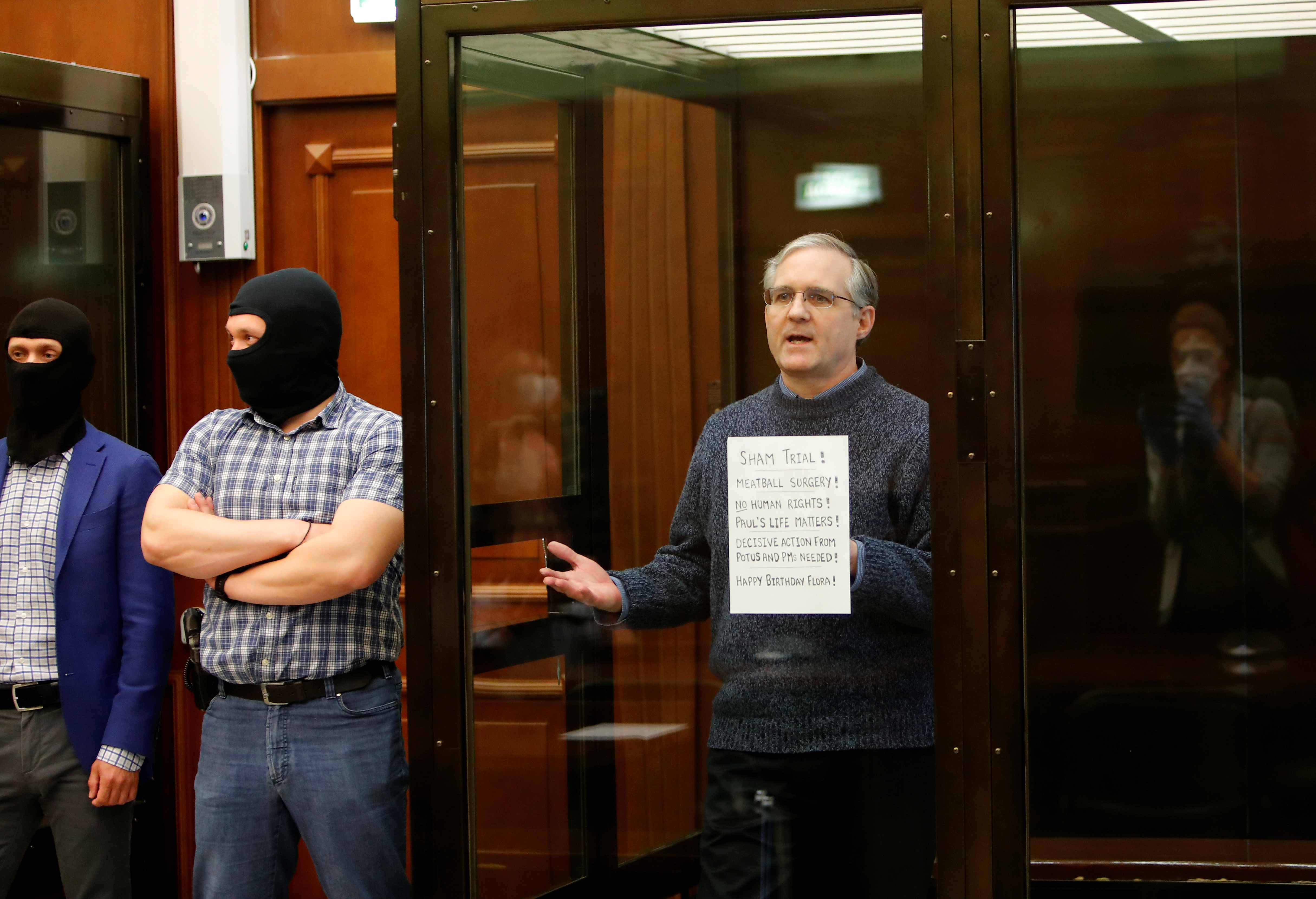 Former U.S. Marine Paul Whelan, who was detained and accused of espionage, holds a sign as he stands inside a defendants' cage during his verdict hearing in Moscow, Russia June 15, 2020. 