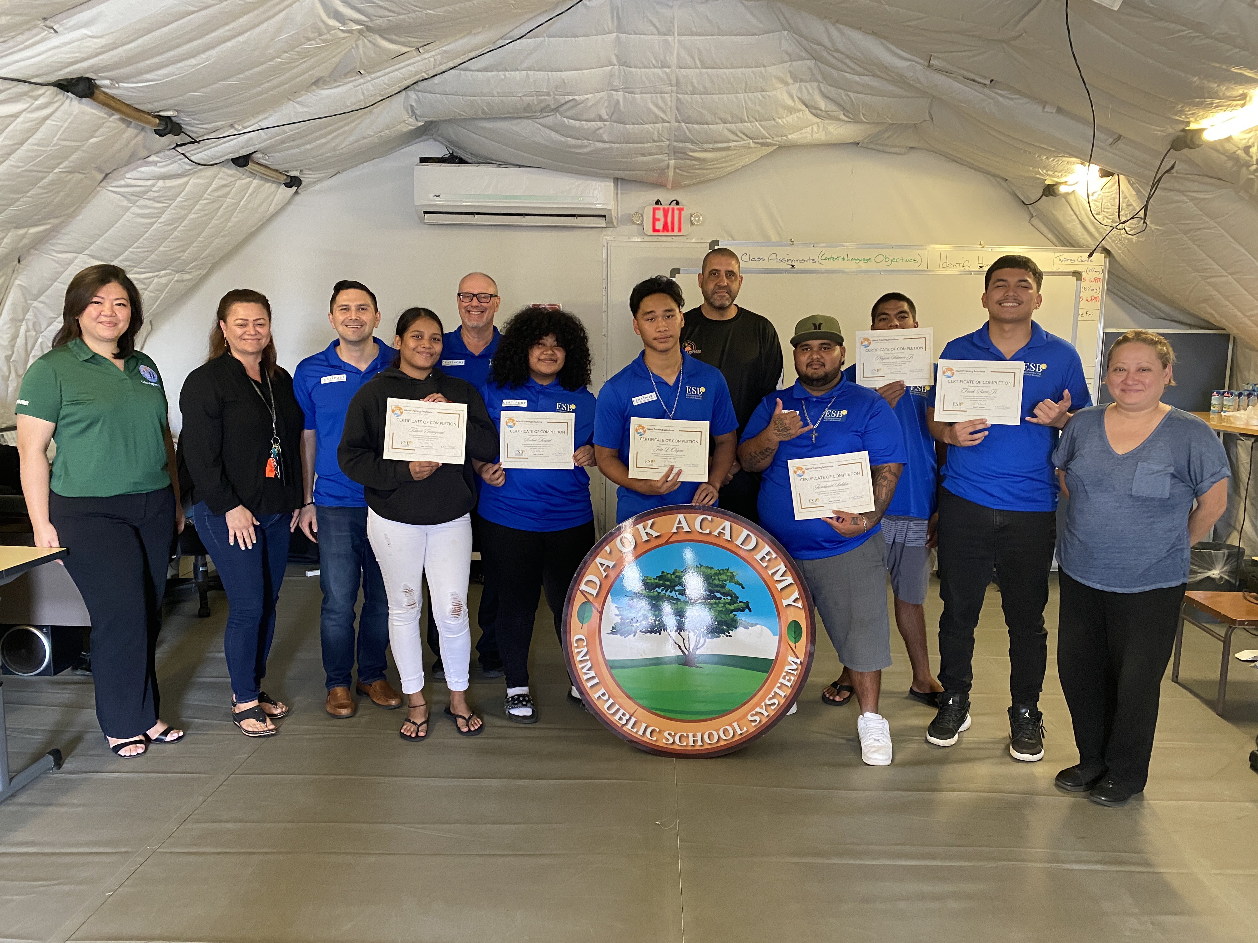 Da'ok Academy students who completed the  Entrepreneurship and Small Business certification course pose for a photo with Da'ok Academy Principal Christine Tudela, Island Training Solutions' Jim Arenovski and Alex Wu, and representatives from the Public School System.  The students holding their certificates are Kiana Emangmai, Senline Kaipat, Jose Olopai, Jeen Sablan, Naysin Solomon and Frank Baza.