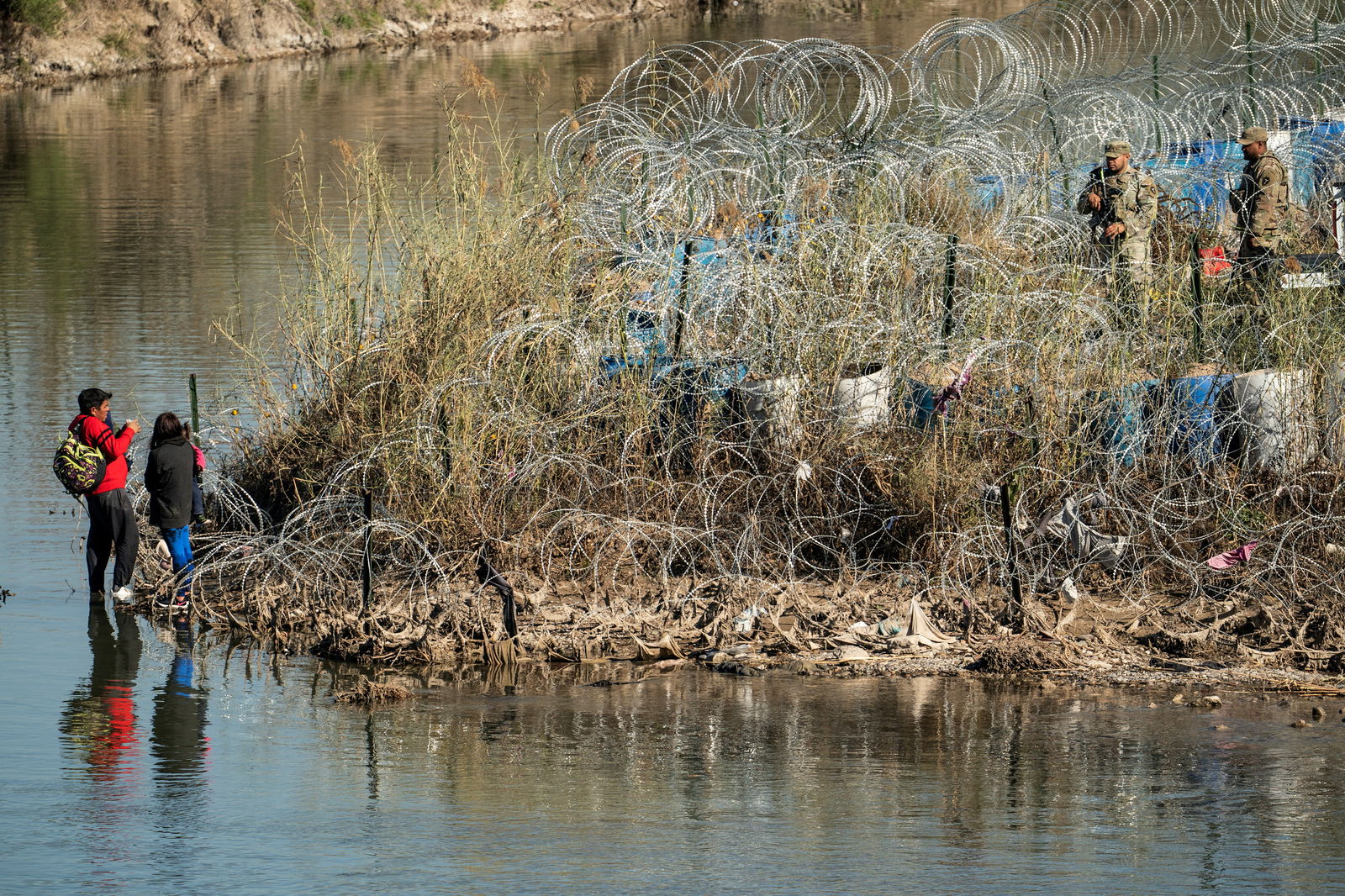 A migrant family talks to the members of U.S. National Guard after crossing the Rio Grande river in Eagle Pass, Texas, as seen from Piedras Negras, Mexico, January 18, 2024. 