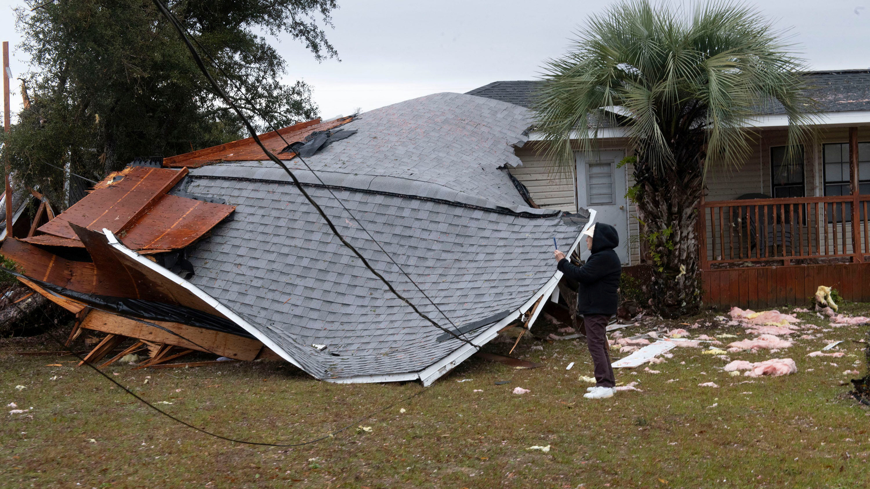 A resident checks a collapsed roof after a line of storms roared through the area of Perdido Key near Pensacola, Florida, U.S. January 9, 2024. 