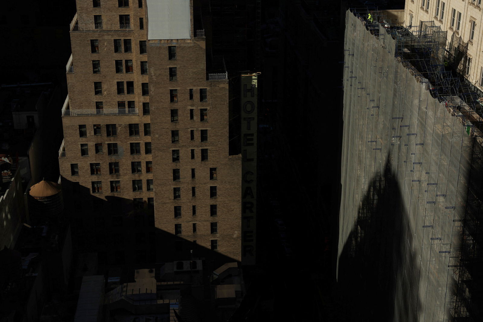 A construction worker stands above the scaffolding of a building in the Times Square area of New York City, U.S., December 20, 2023. 