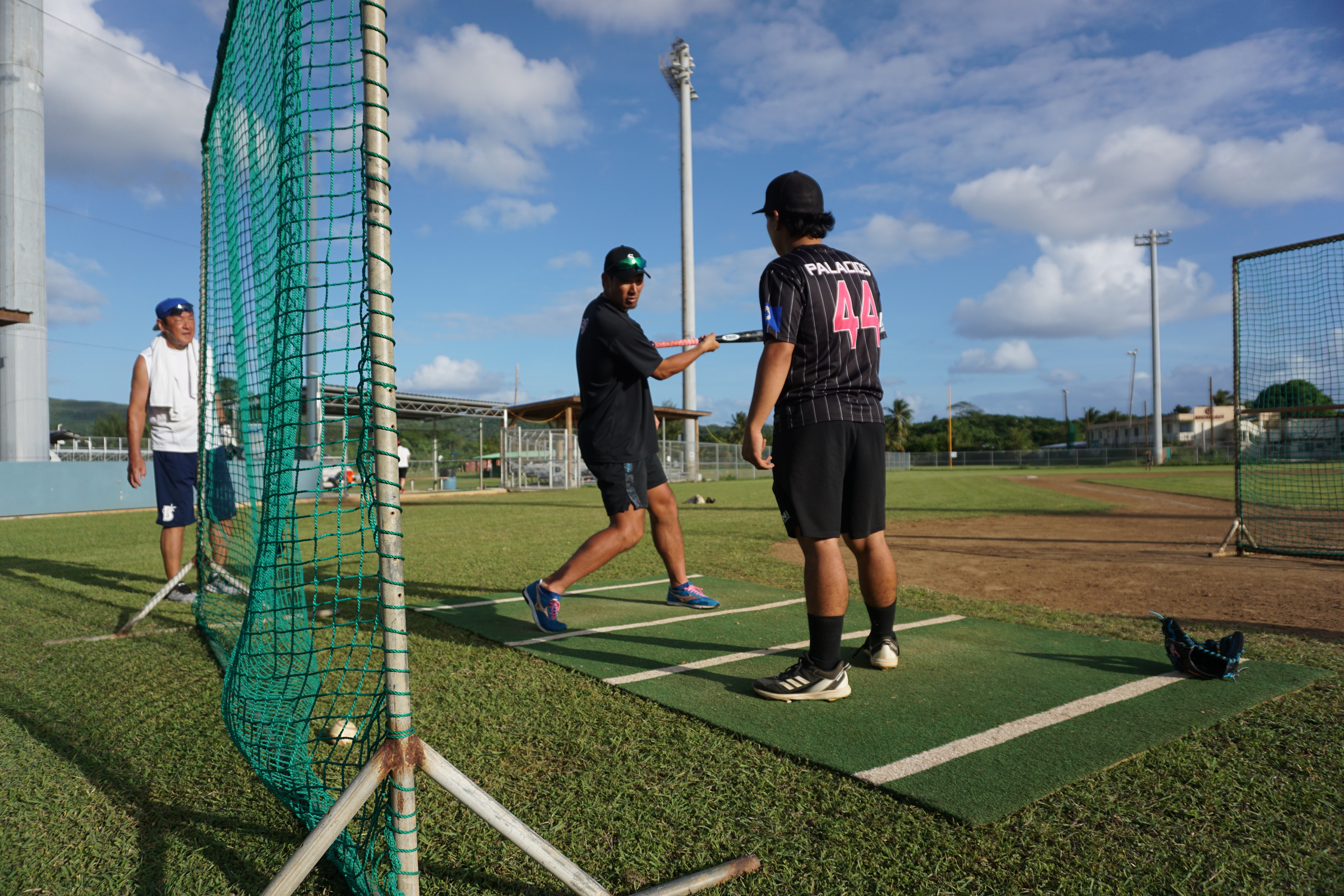 Japanese baseball player Taishi Ohta teaches a participant the technique of swinging during a baseball clinic at the Francisco “Tan Ko” Palacios Baseball Field on Saturday.