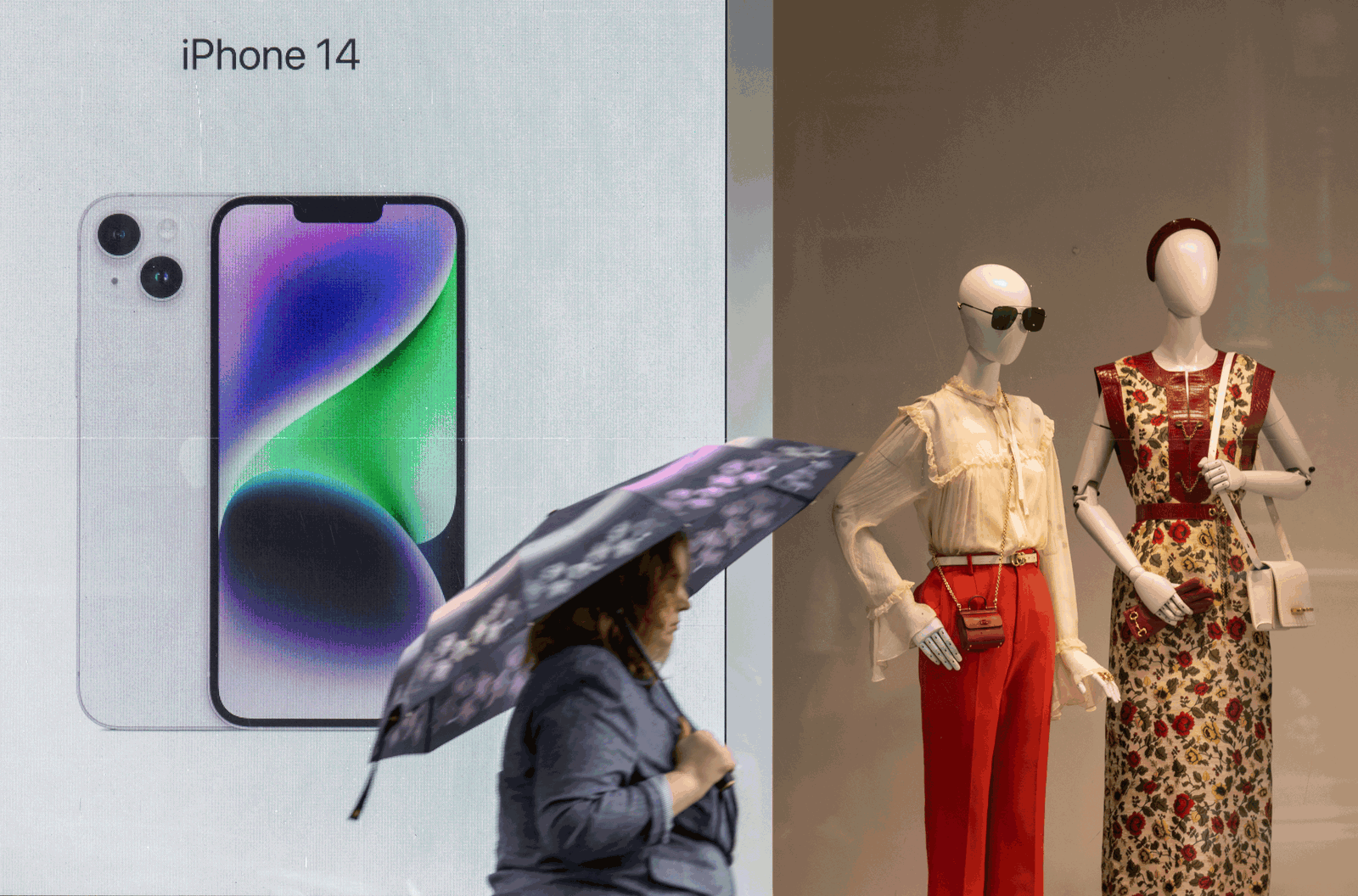 A woman with an umbrella walks past a display advertising Apple iPhone 14 during rainy weather in Moscow, Russia May 25, 2023. 