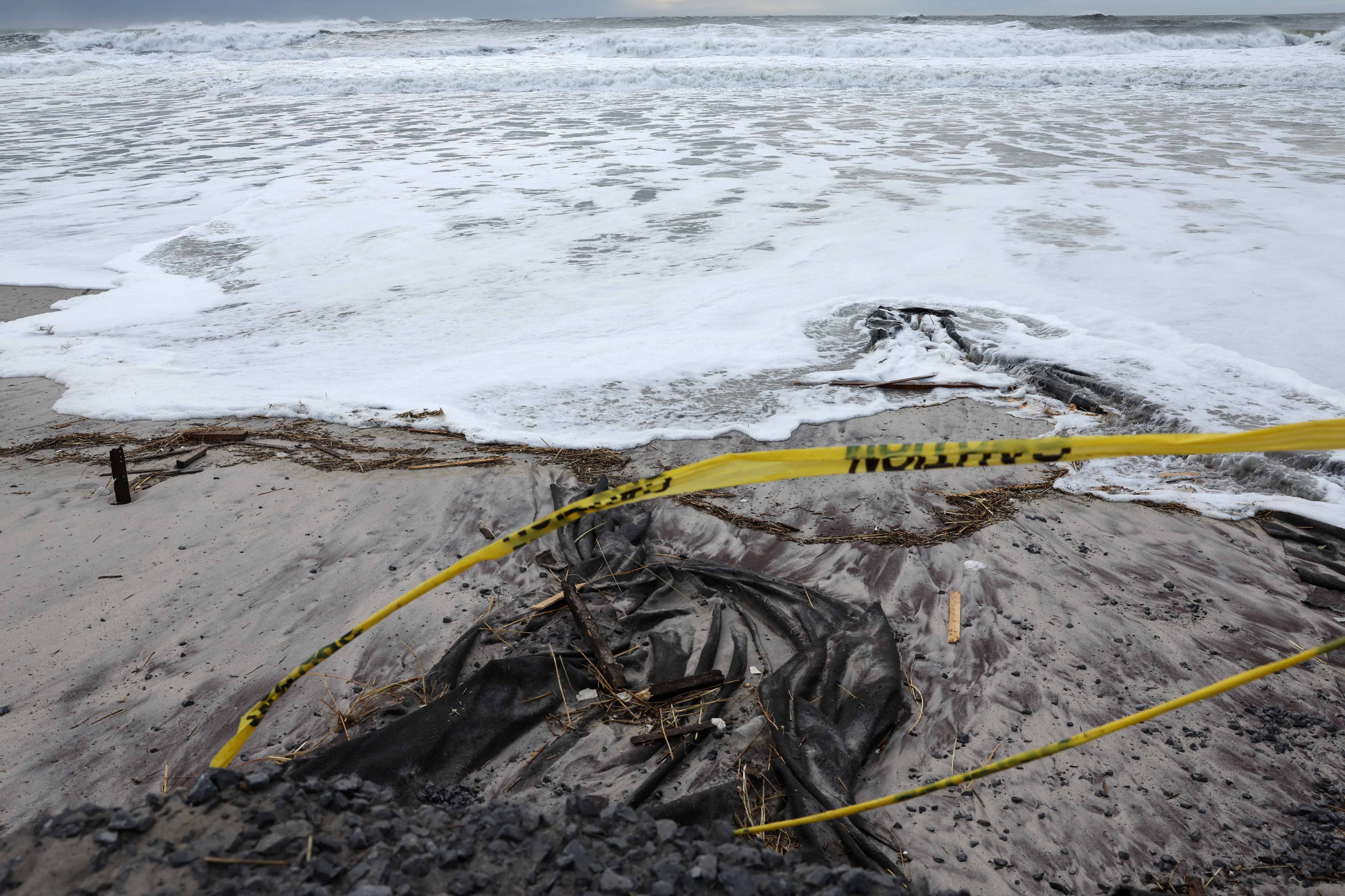 Caution tape whips in the wind as waves rush the beach during the pass of a winter storm in Lido Beach, New York, U.S., January 10, 2024. 