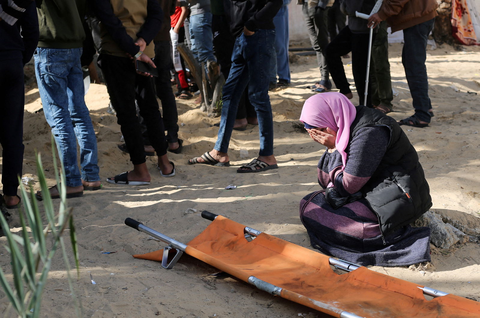A woman reacts while people bury bodies of Palestinians killed in an Israeli strike, at the Nasser hospital premises as Palestinians cannot reach the cemetery due to the Israeli ground operation, in Khan Younis in the southern Gaza Strip, January 22, 2024. 