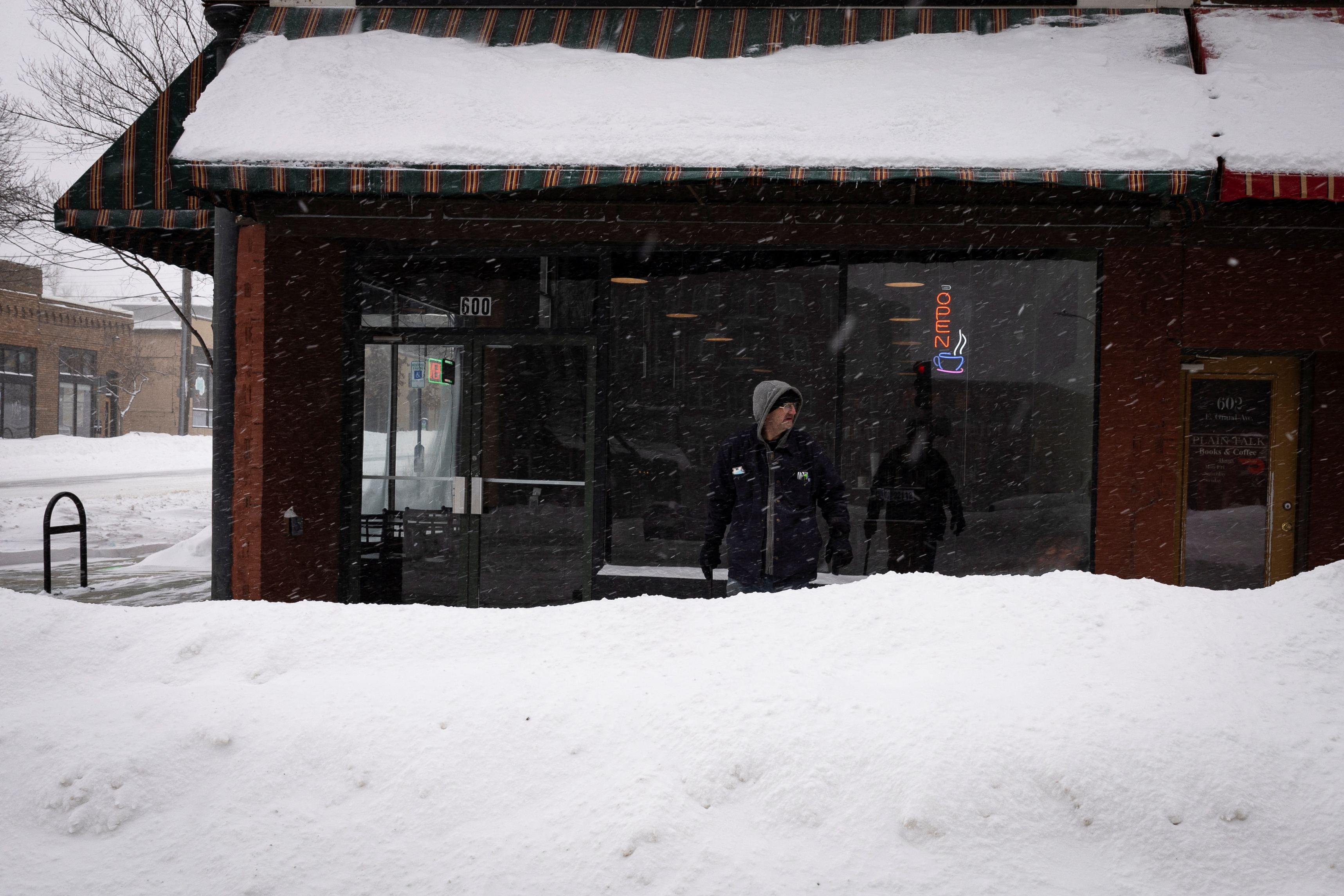 A man stands outside a coffee shop after a blizzard left several inches of snow, in downtown Des Moines, Iowa, U.S., January 13, 2024. 