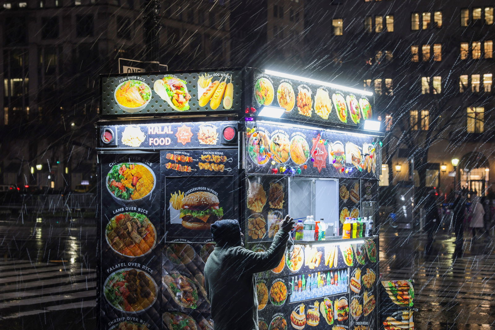 A person films the snow next to a food cart as snow falls in New York City, U.S., January 6, 2024.