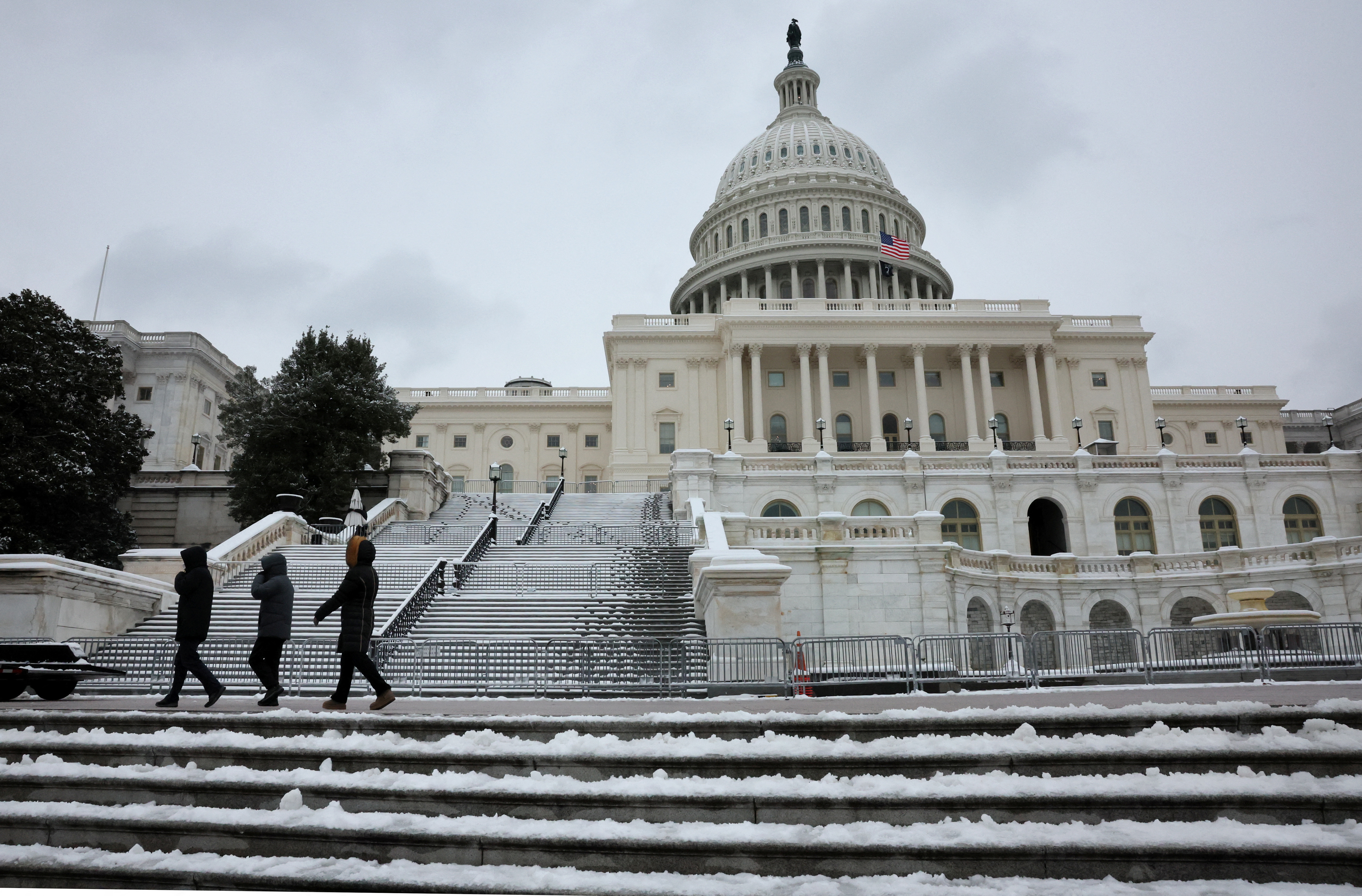 People walk past a snowy U.S. Capitol building in Washington, D.C., Jan. 16, 2024.