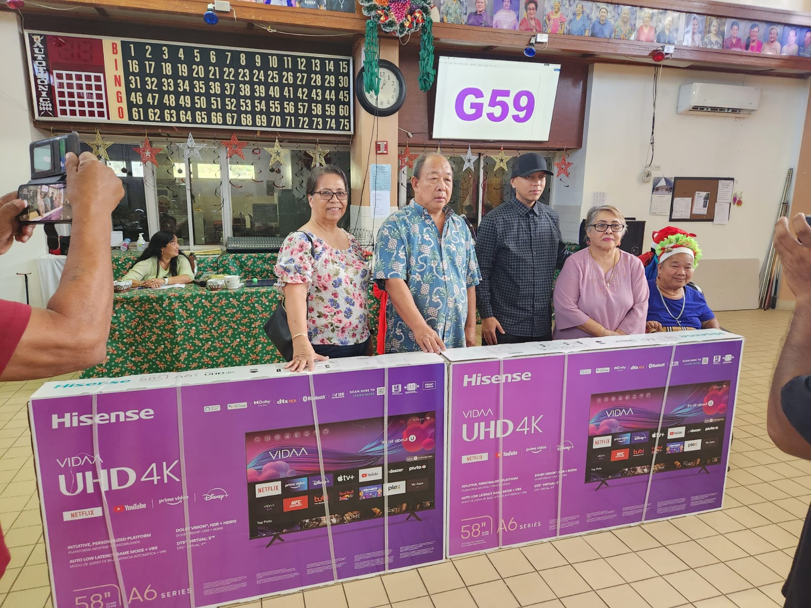 Business consultant Patricia Songsong and Changhong Corp. owner Yong Lin, who donated two smart TVs, pose for a photo with Office on Aging Director Walter Manglona and some of the senior citizens at the manamko’ center.