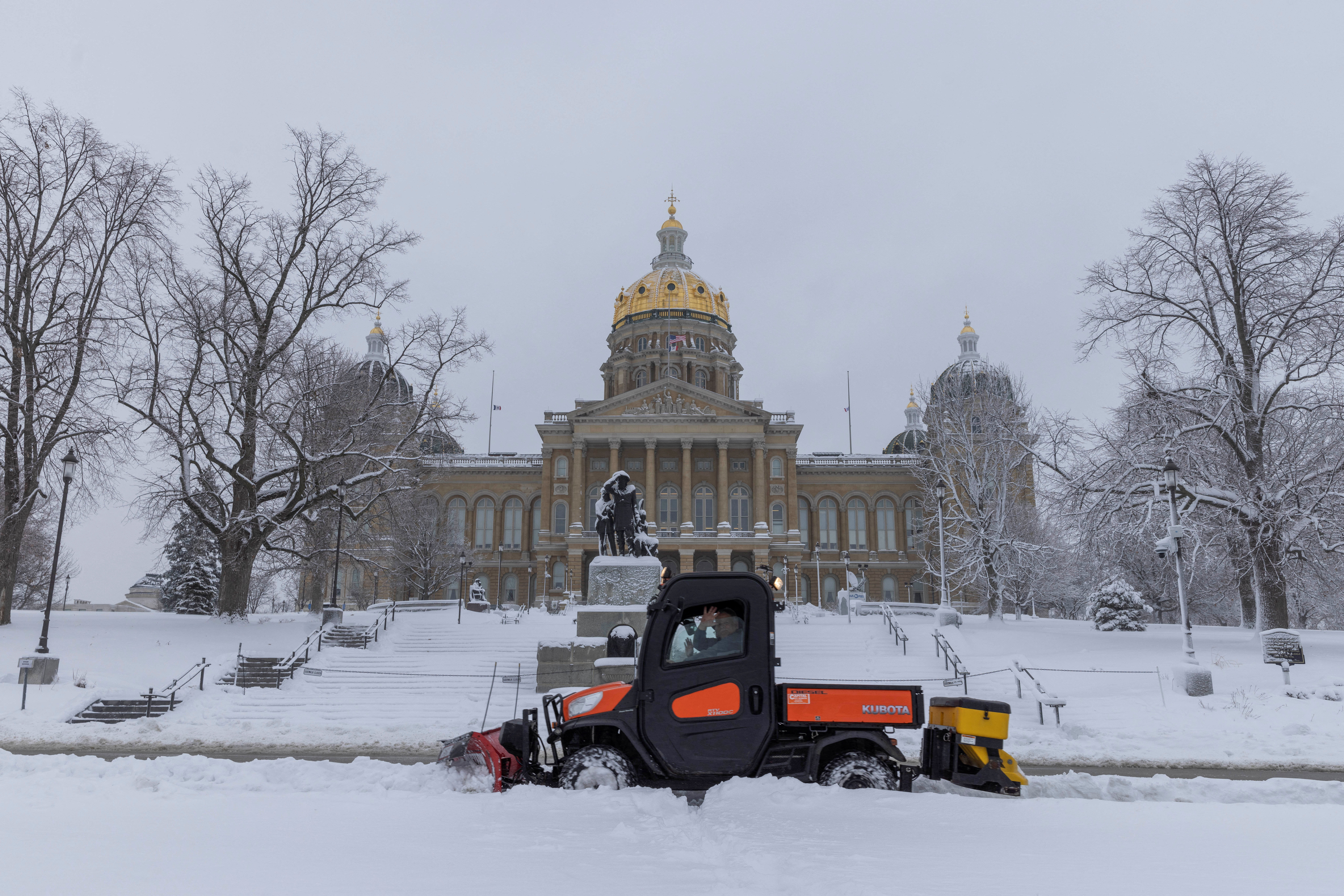 Workers remove snow from the sidewalk outside of the Iowa State Capitol Building after a snowstorm left several inches of snow in Des Moines, Iowa, U.S., January 9, 2024. 