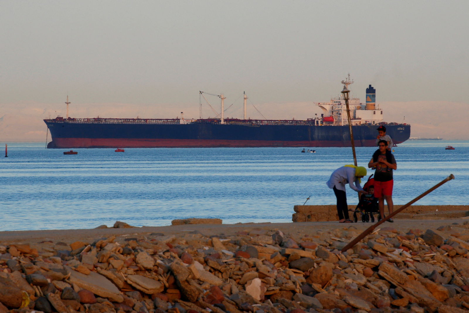 People walk on the beach as a container ship crosses the Gulf of Suez towards the Red Sea before entering the Suez Canal, in El Ain El Sokhna in Suez, east of Cairo, Egypt April 24, 2017.