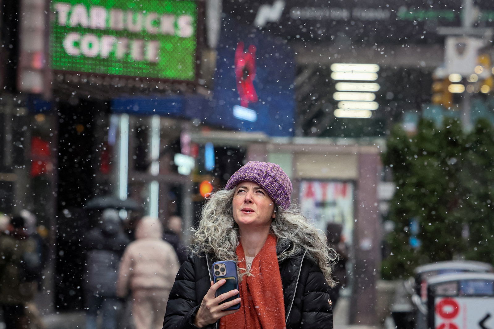 People walk through Times Square as the snow falls during a winter storm in New York City, U.S., January 19, 2024. 