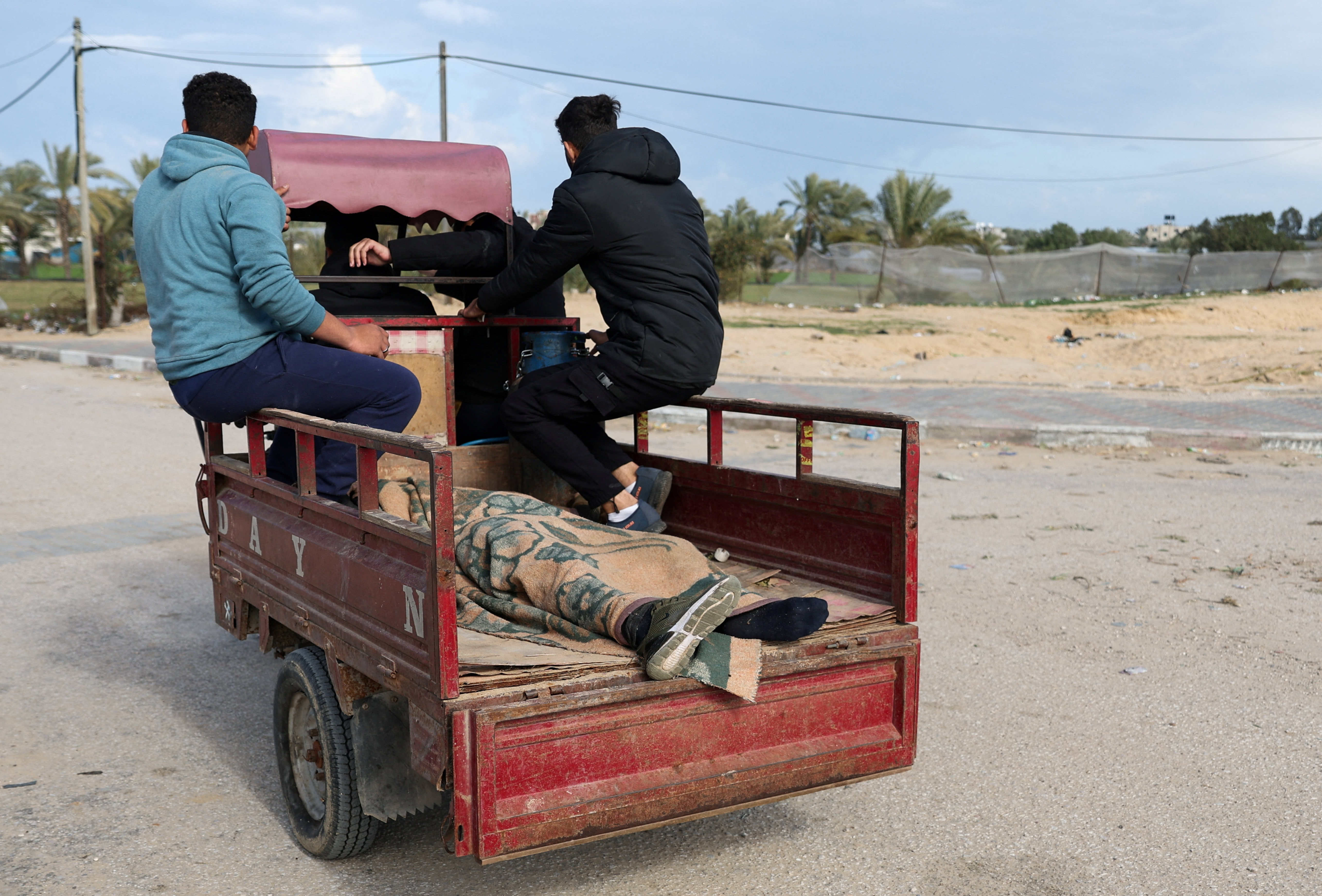 The body of a Palestinian killed in an Israeli strike lies in the back of a vehicle, as Palestinians fleeing Khan Younis, due to the Israeli ground operation, move towards Rafah, amid the ongoing conflict between Israel and the Palestinian Islamist group Hamas, in the southern Gaza Strip, January 28, 2024. 
