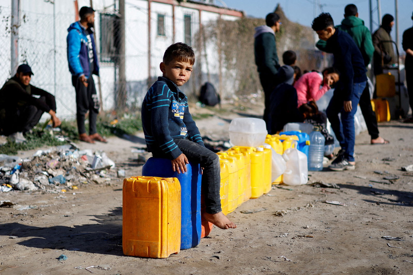A displaced Palestinian boy, who fled his house due to Israeli strikes, sits on a water canister at a tent camp, amid the ongoing conflict between Israel and the Palestinian Islamist group Hamas, in Rafah in the southern Gaza Strip, January 18, 2024. 